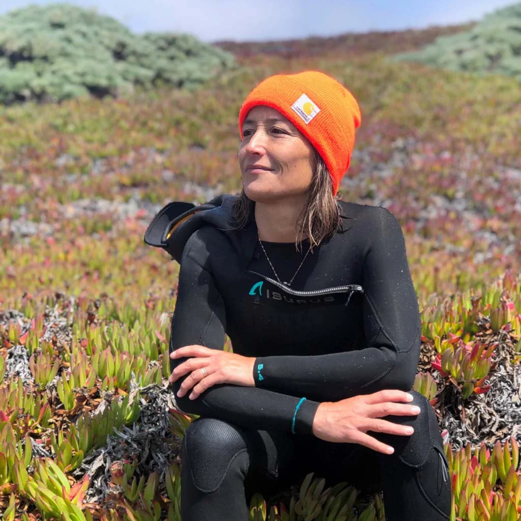sachi_cunningham_women_s_japanese_yamamototo_5.4_hooded_wetsuit_surfing_sittingonbeachskyfxd-work-pants-lifestyle_5000x.webp