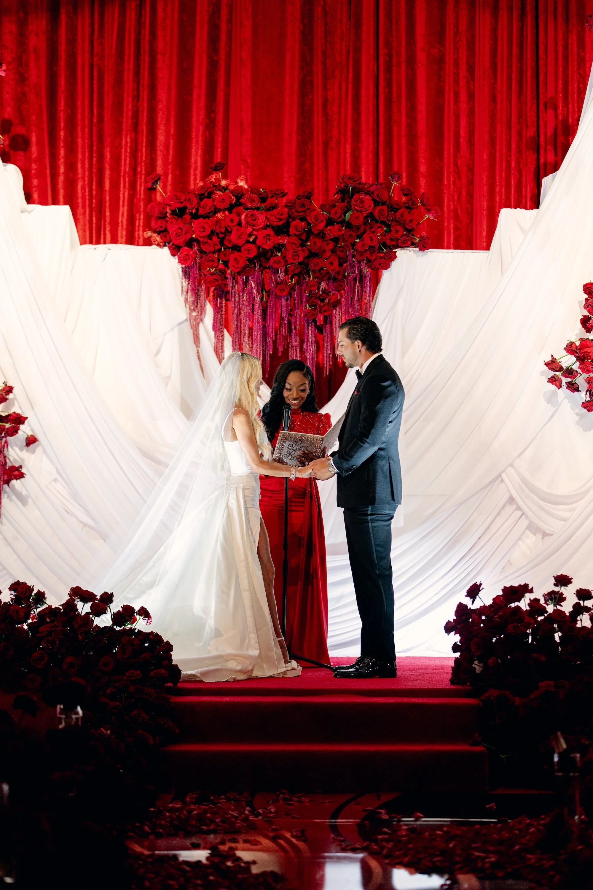 Reverend Roxy at luxe red destination wedding with white custom ceremony backdrop. Luxury Las Vegas Wedding Planner Andrea Eppolito.