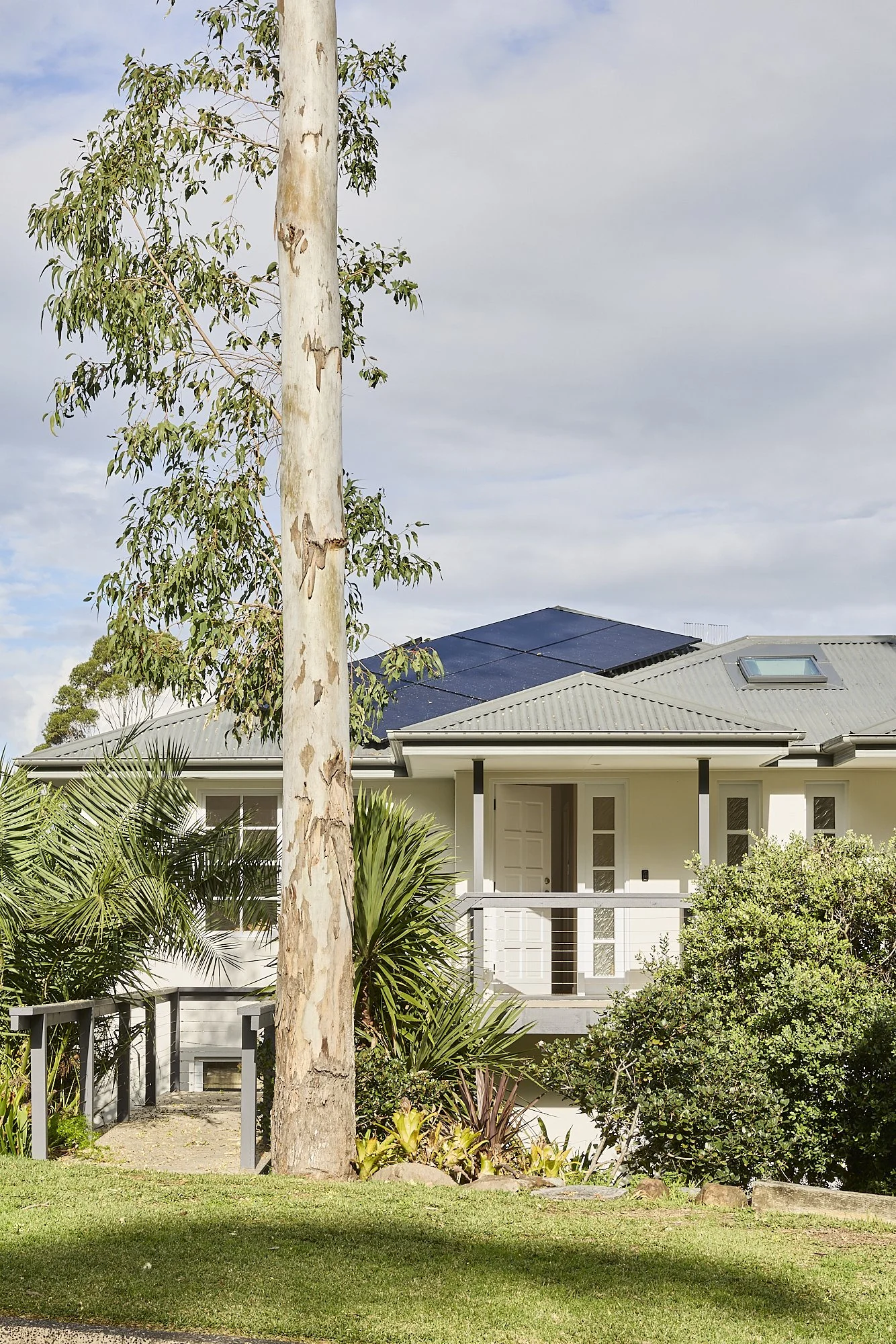 Contemporary Australian coastal home exterior with landscaped native garden, elevated verandah, metal roof and solar panels designed for relaxed family living.
