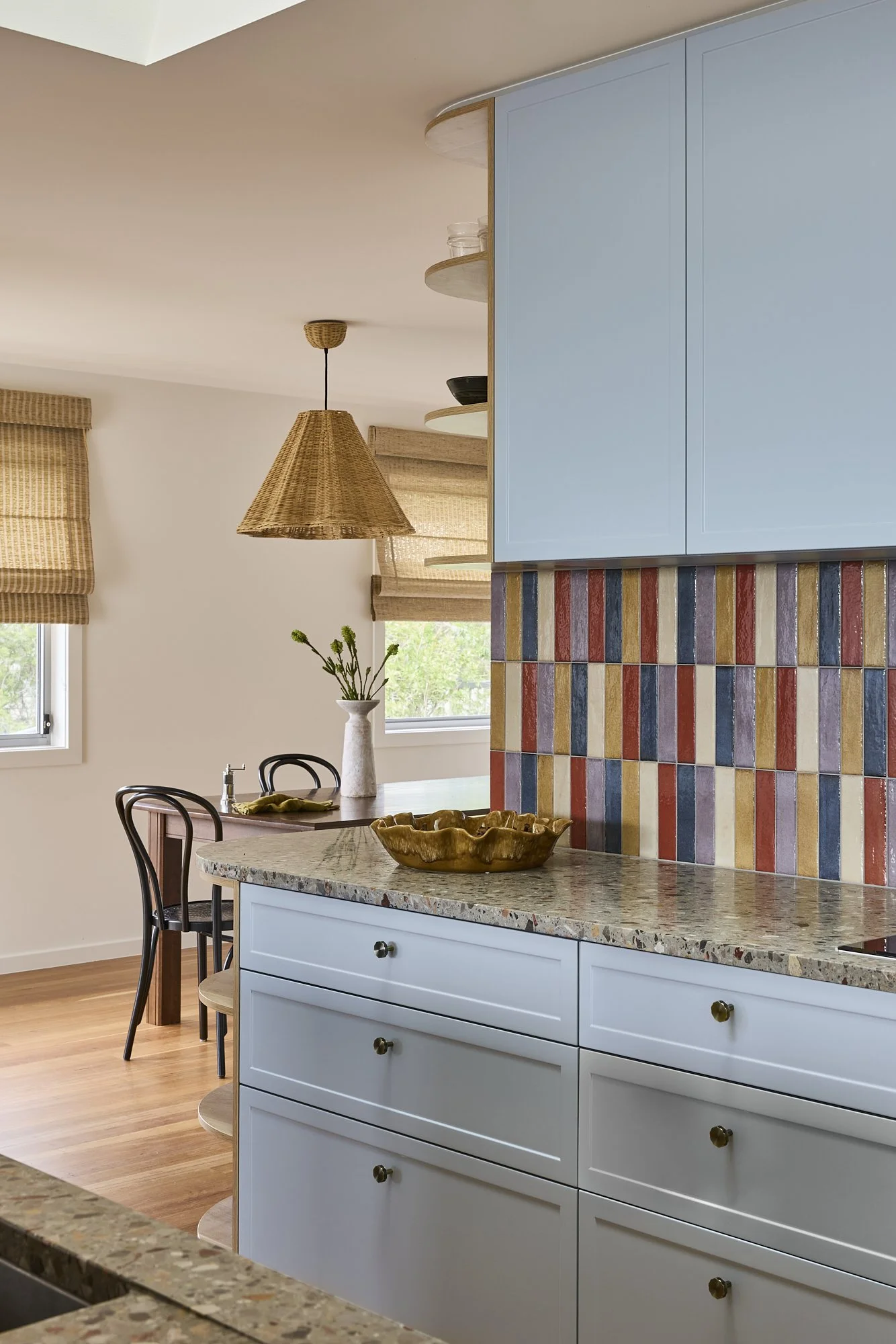 Contemporary kitchen with colourful handcrafted tiled island, terrazzo benchtops, pale blue joinery and warm oak detailing in a bespoke Australian coastal home.