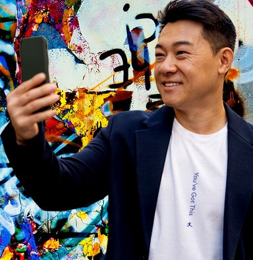 A happy good looking guy is in a blue sports coat with a great white tee shirt. You can see printed on the center of shirt the message "You've Got This"! He's taking a selfie. It's not just a tee shirt...it's a morale boost as well!