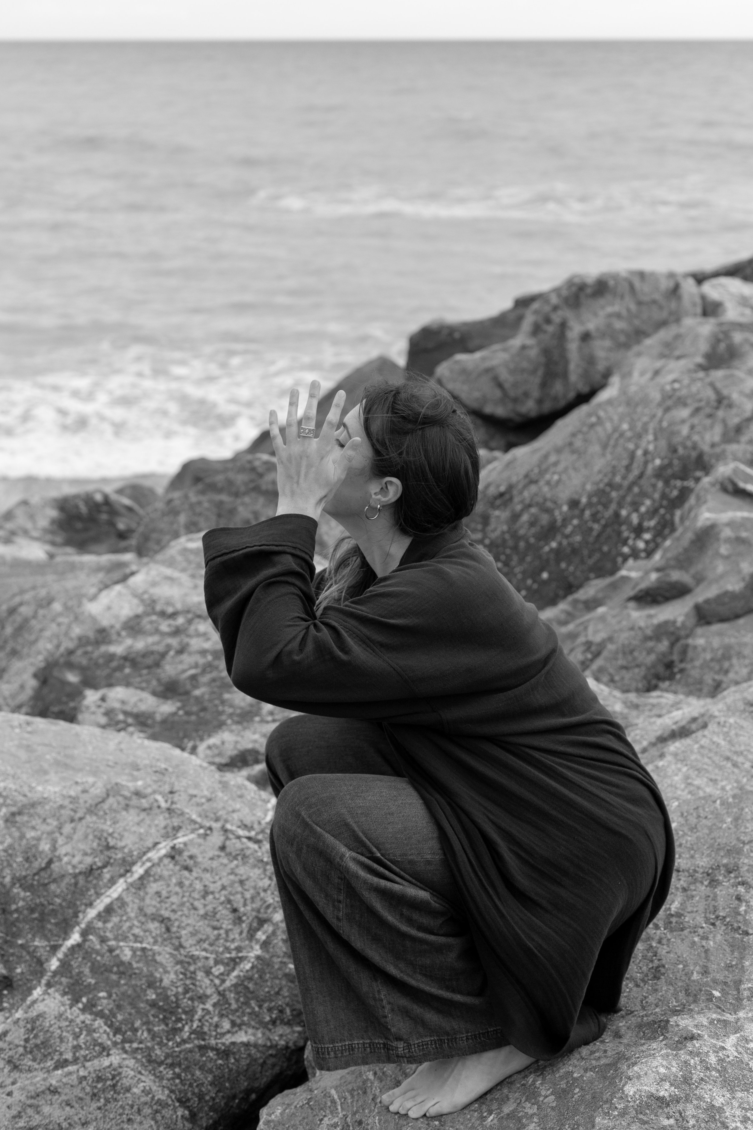 Hypnotherapist in Bristol, specialising in anxiety and burnout, seated on beach in black and white