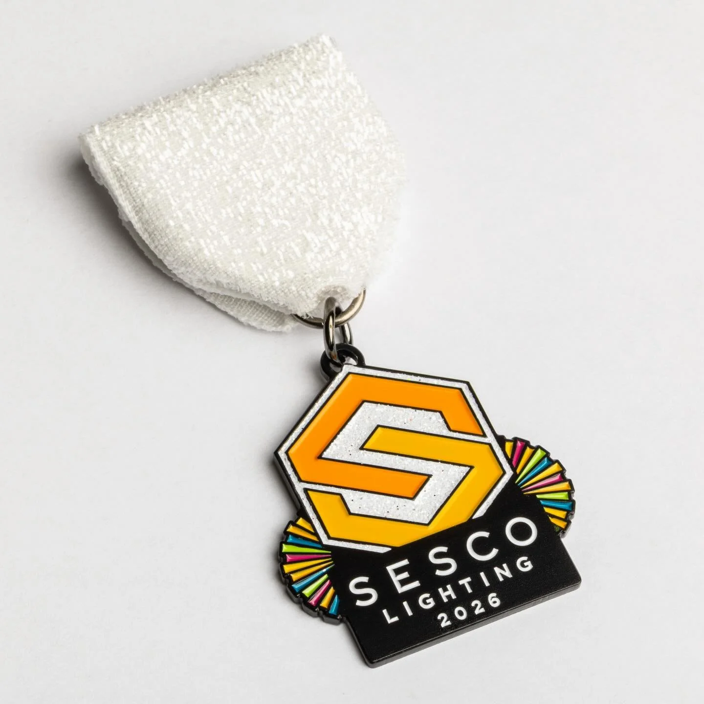 Get ready to shine, Fiesta fans! The Fiesta medal Core Creative designed for SESCO Lighting features vibrant bursts of color, complete with a white glitter ribbon and a sparkling glitter logo that will light up the season. It&rsquo;s bold, bright, an