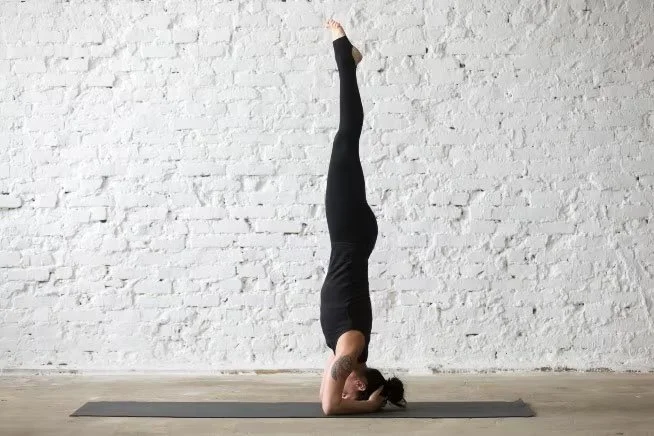 Femme allongée avec un bandage pour les yeux, portant un t-shirt noir, sur un tapis noir.