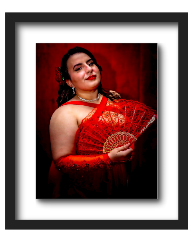 A woman dressed in a red outfit with lace details, holding a red lace fan, with dark hair and makeup, standing against a dark red background.