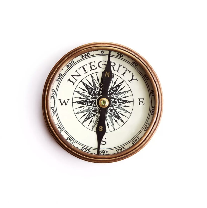 A compass with a copper-colored frame, displaying cardinal directions and the word 'INTEGRITY' on the face, pointing north.