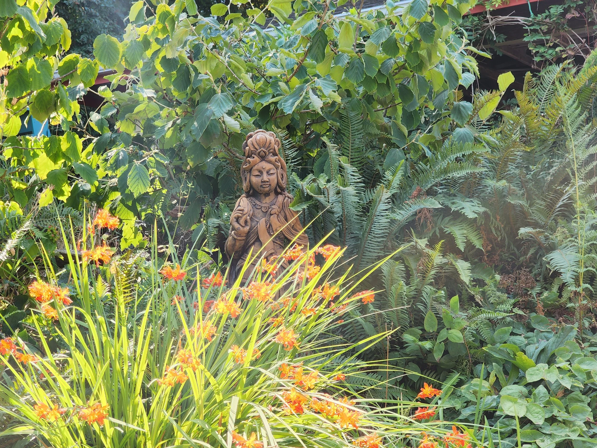 Garden view from Rochelle’s office with greenery and a Quan Yin statue.