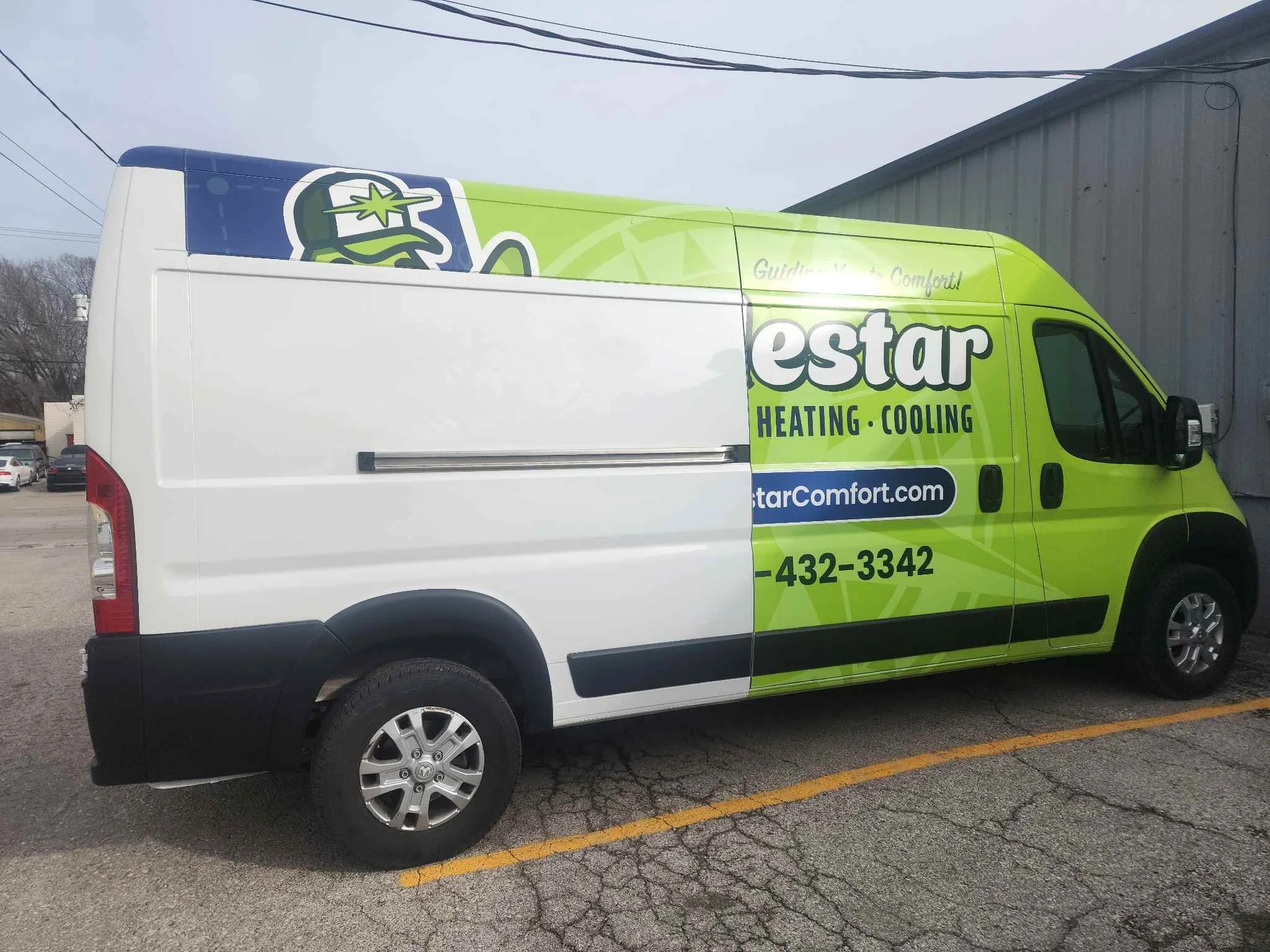 A green and white service van parked in a parking lot next to a gray metal building. The van is branded with the company name 'E-Star' and has text indicating HVAC services.