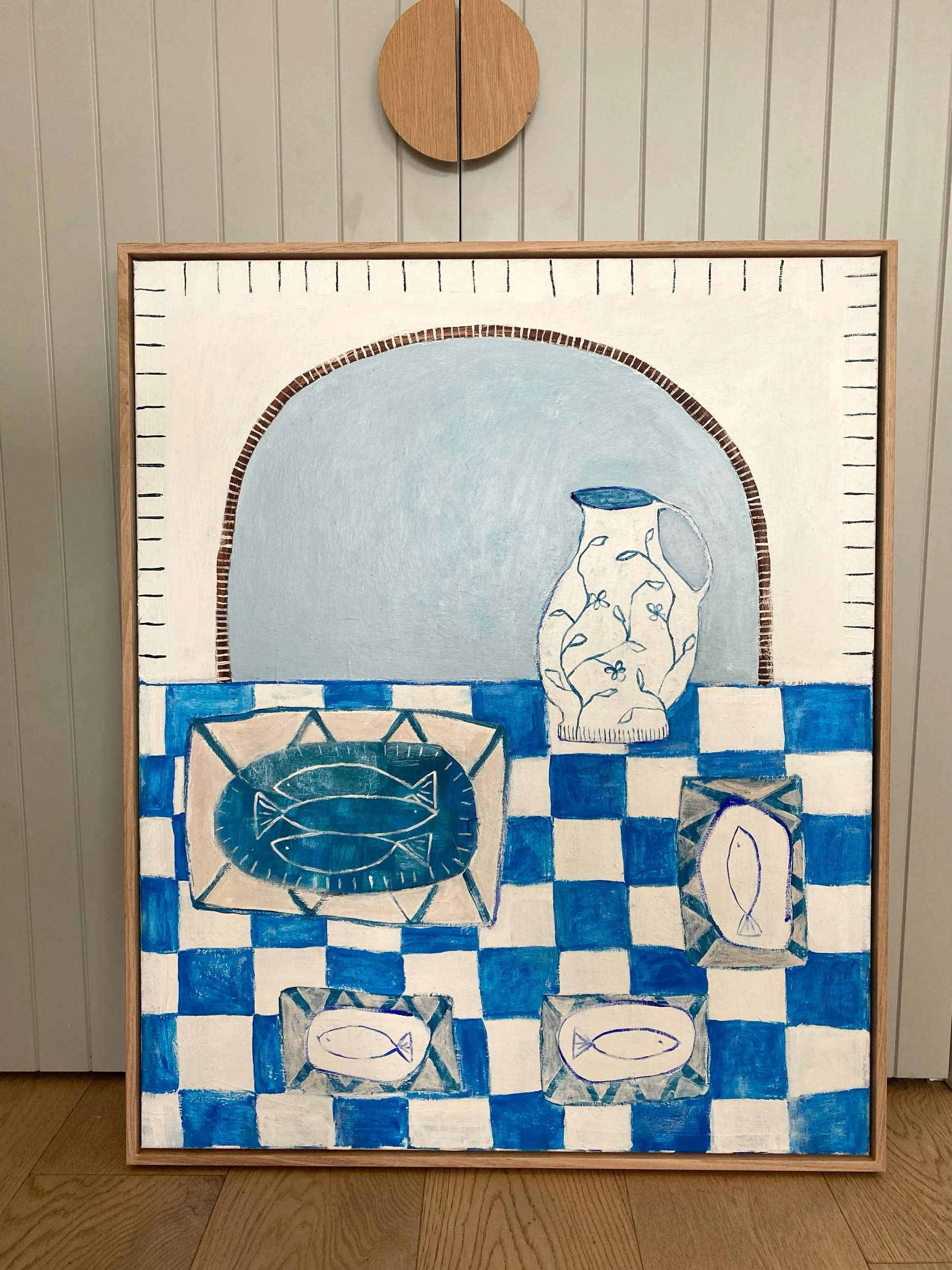 Painting of a still life featuring a jug with floral patterns and several plates on a blue and white checkered tablecloth, with each plate showcasing fish designs, against an arch background.