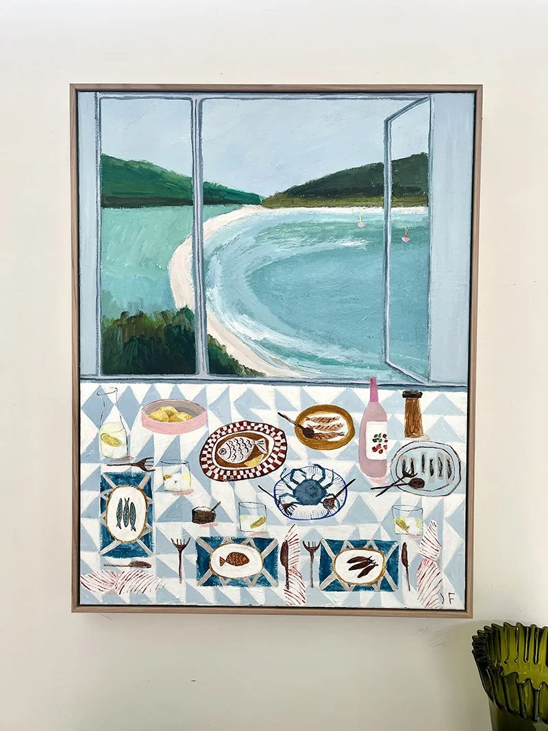 Painting of an open window overlooking a coastal landscape with a beach, water, and green hills. Inside the room, a dining table with a checkered tablecloth is set with plates of seafood, glasses, and utensils.