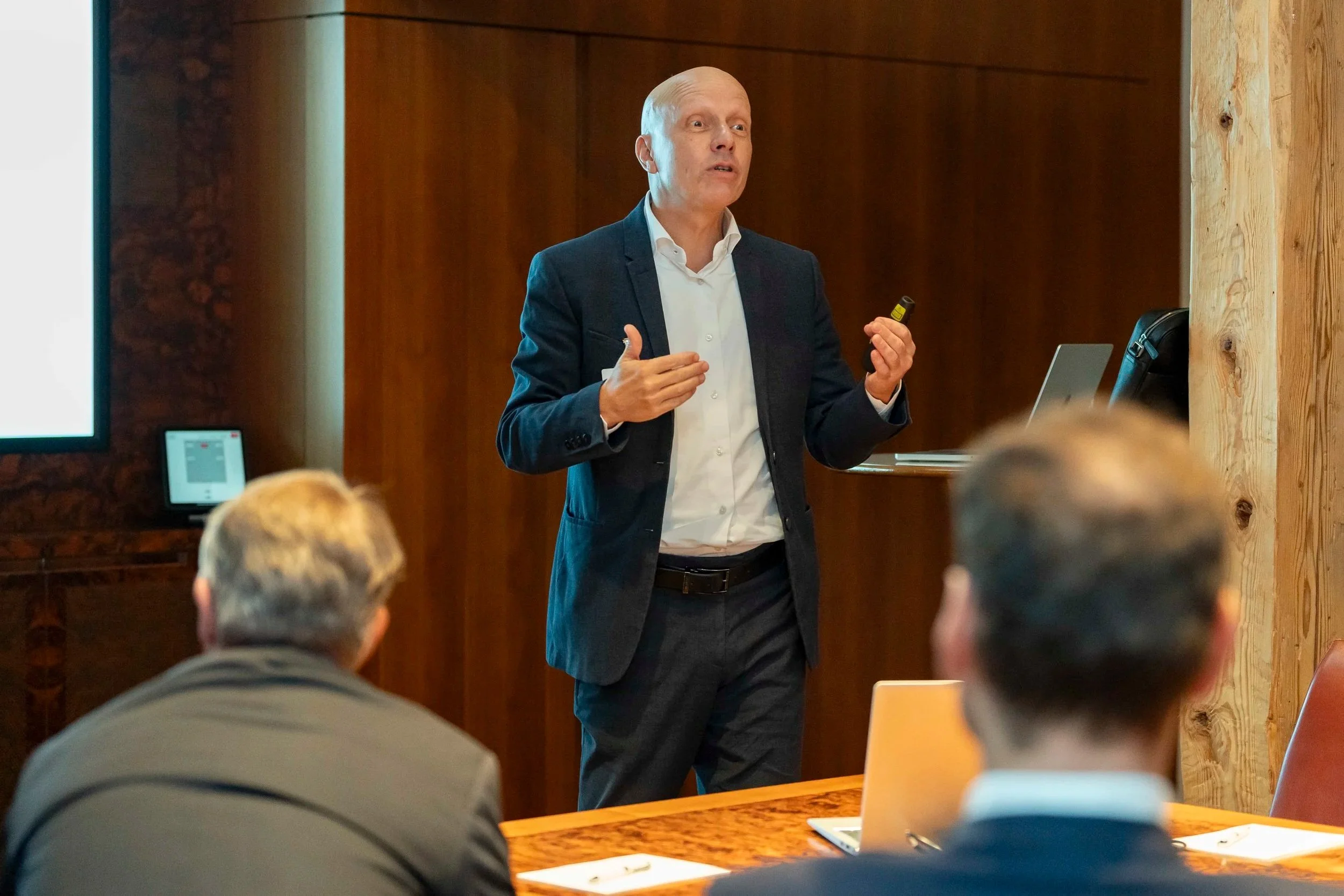 Man in business outfit is standing and talking in front of people