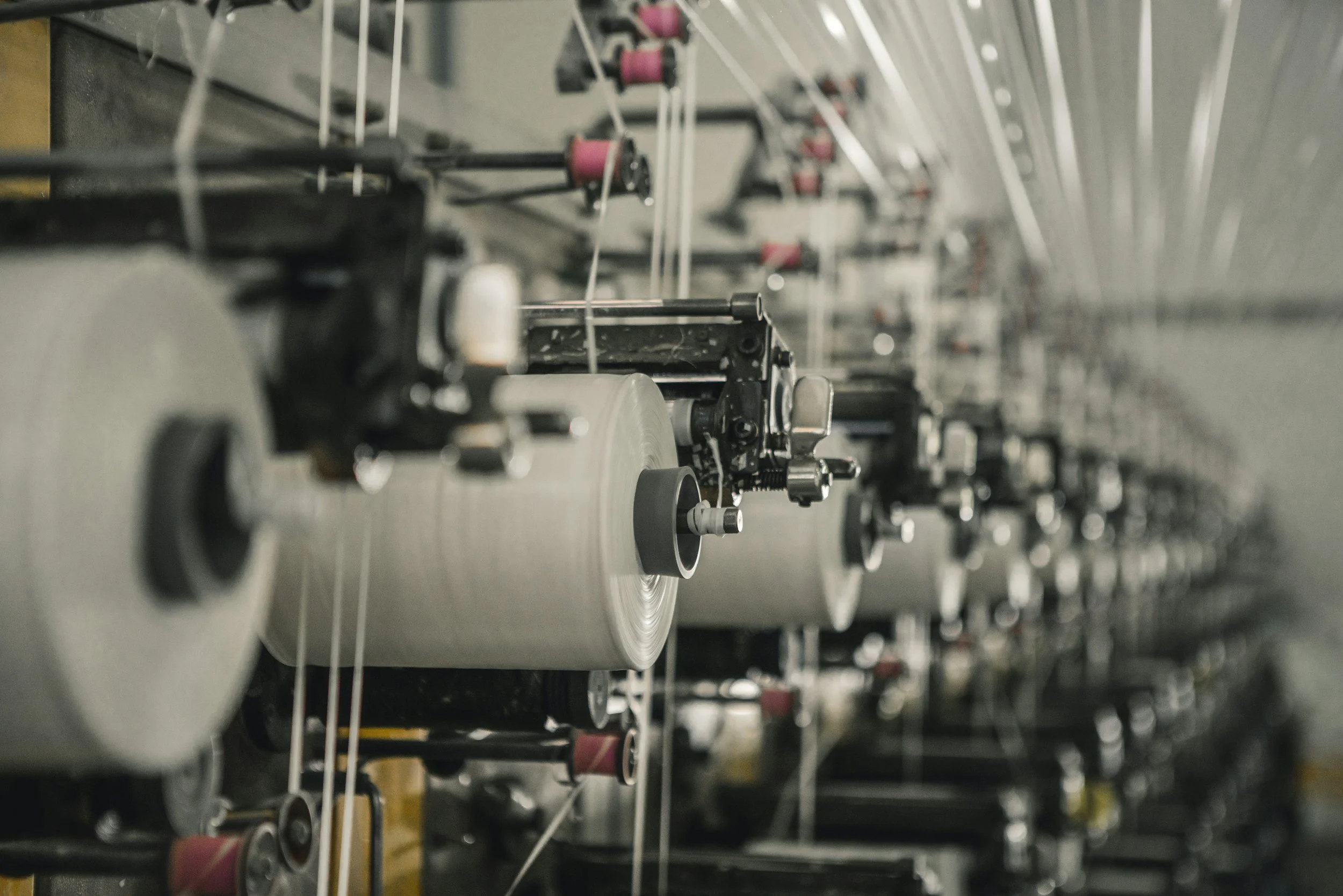 Close-up of industrial machinery producing fabric or paper on a long roll in a factory.