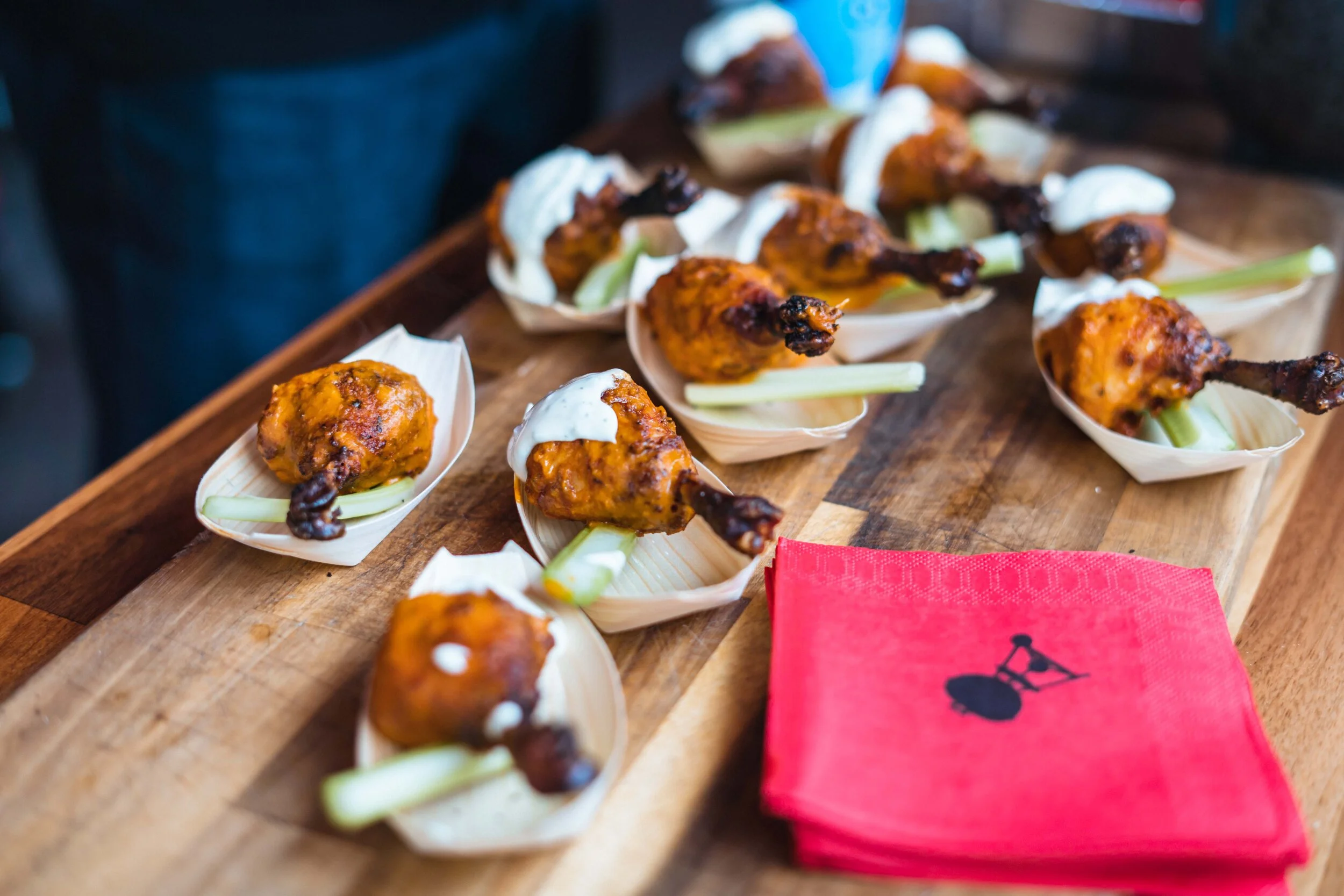 Chicken drumettes on wooden platter with celery and sauce