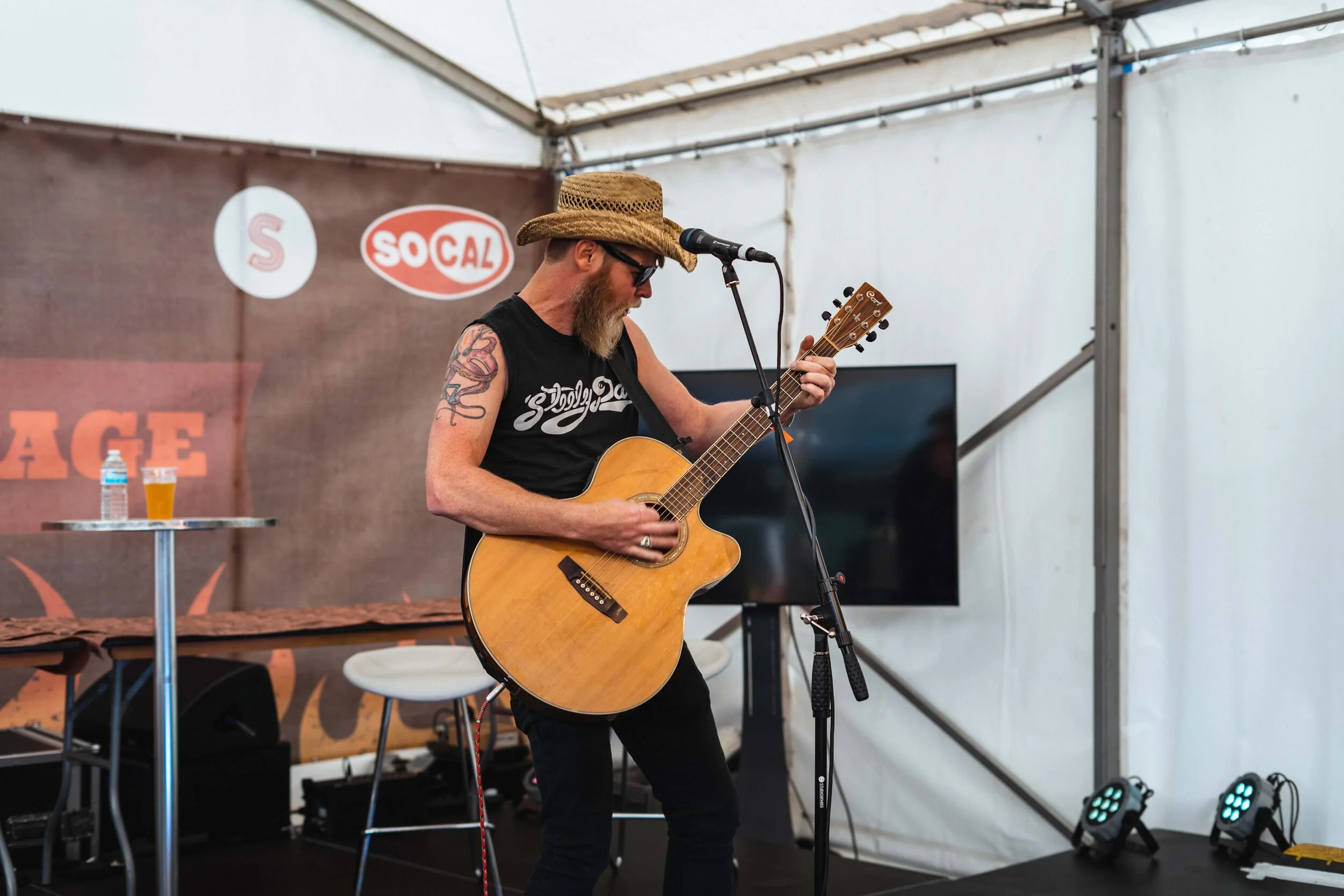 Man playing guitar on stage wearing cowboy hat and sunglasses with amp in background