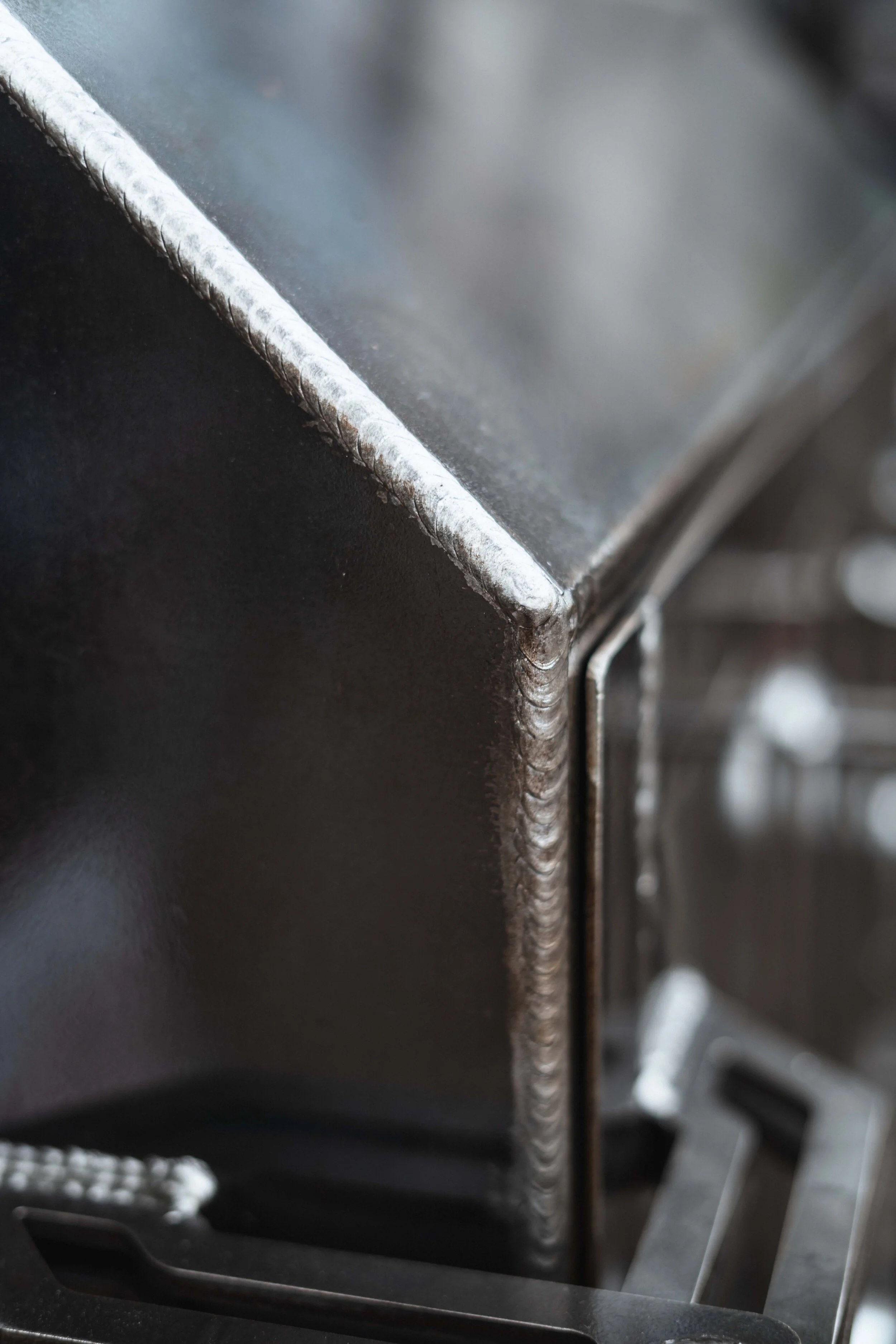 Close-up of a metal fabrication with prominent weld seams at the edges.
