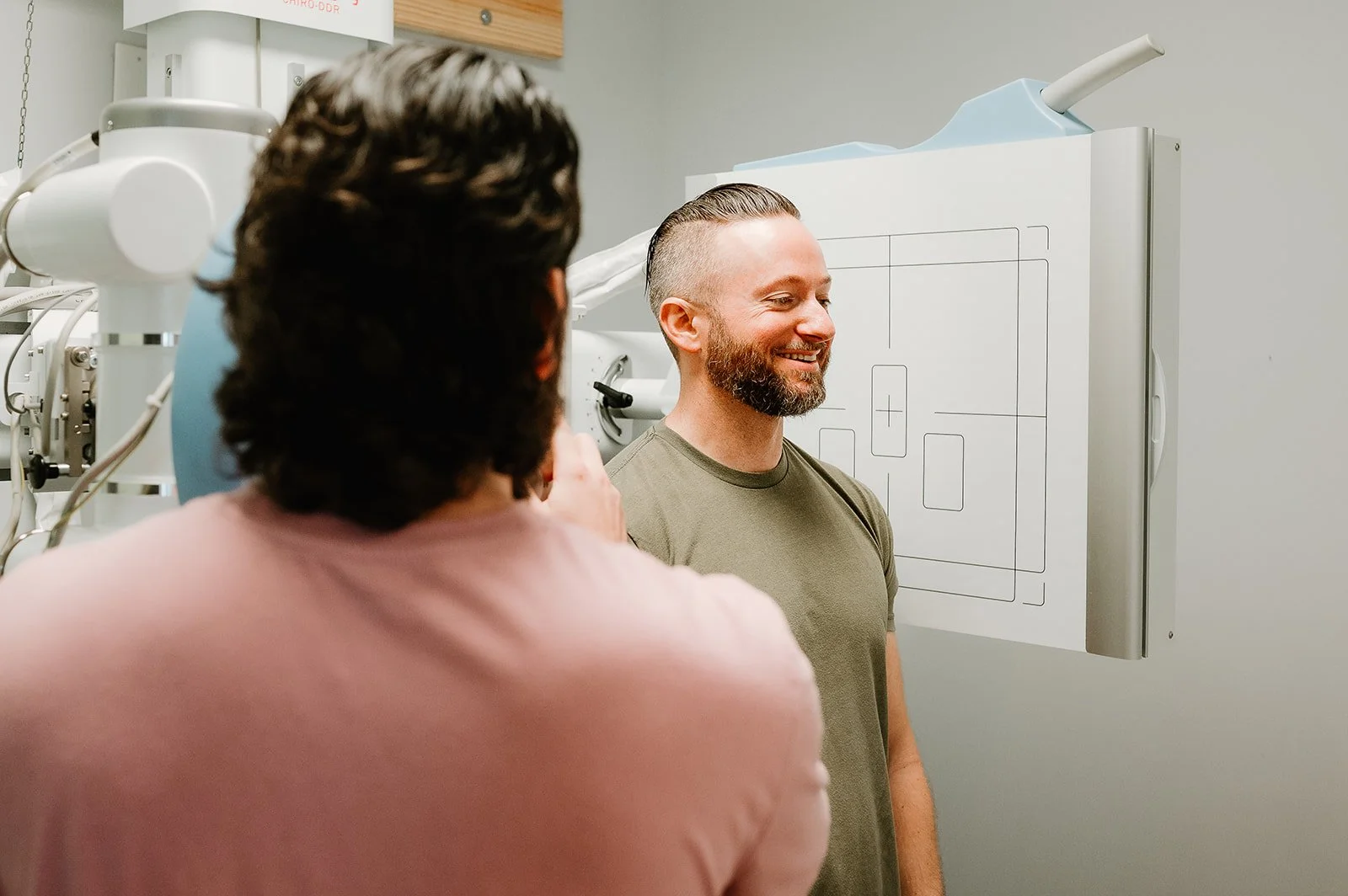 Patient standing in front of a digital motion X-ray (DDR) unit while the chiropractor reviews imaging at MCH Chiropractic in Matthews NC