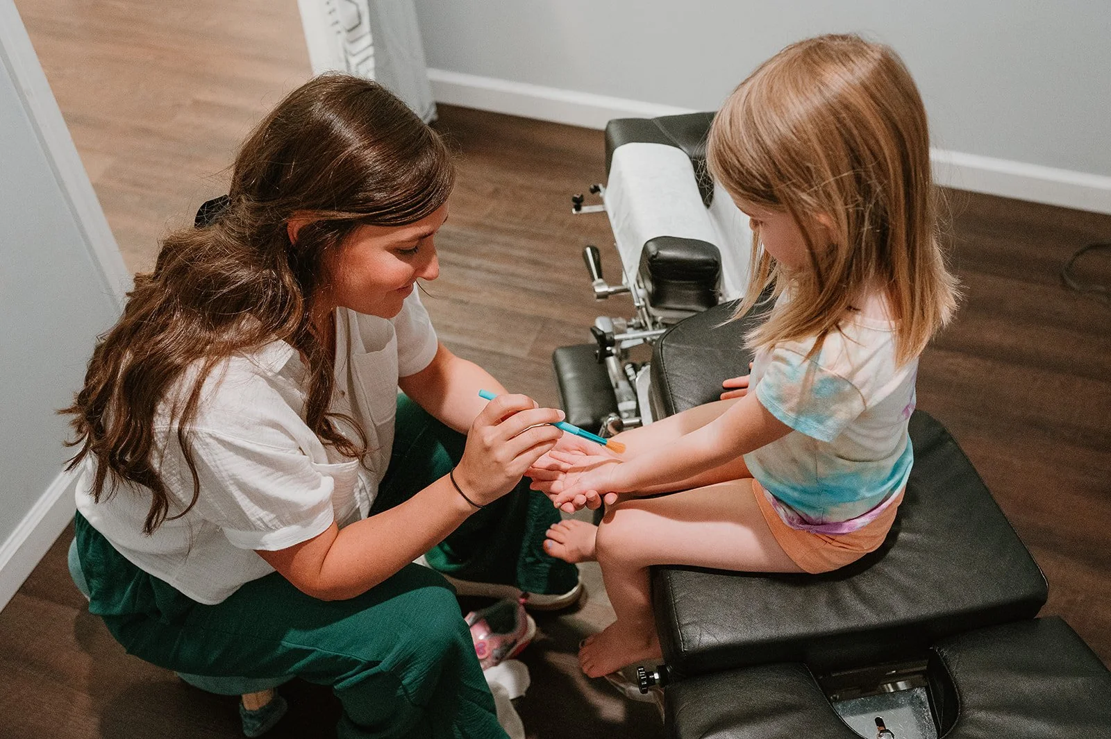 Chiropractor gently checking a young child’s wrist during a pediatric chiropractic visit at MCH Chiropractic in Matthews NC
