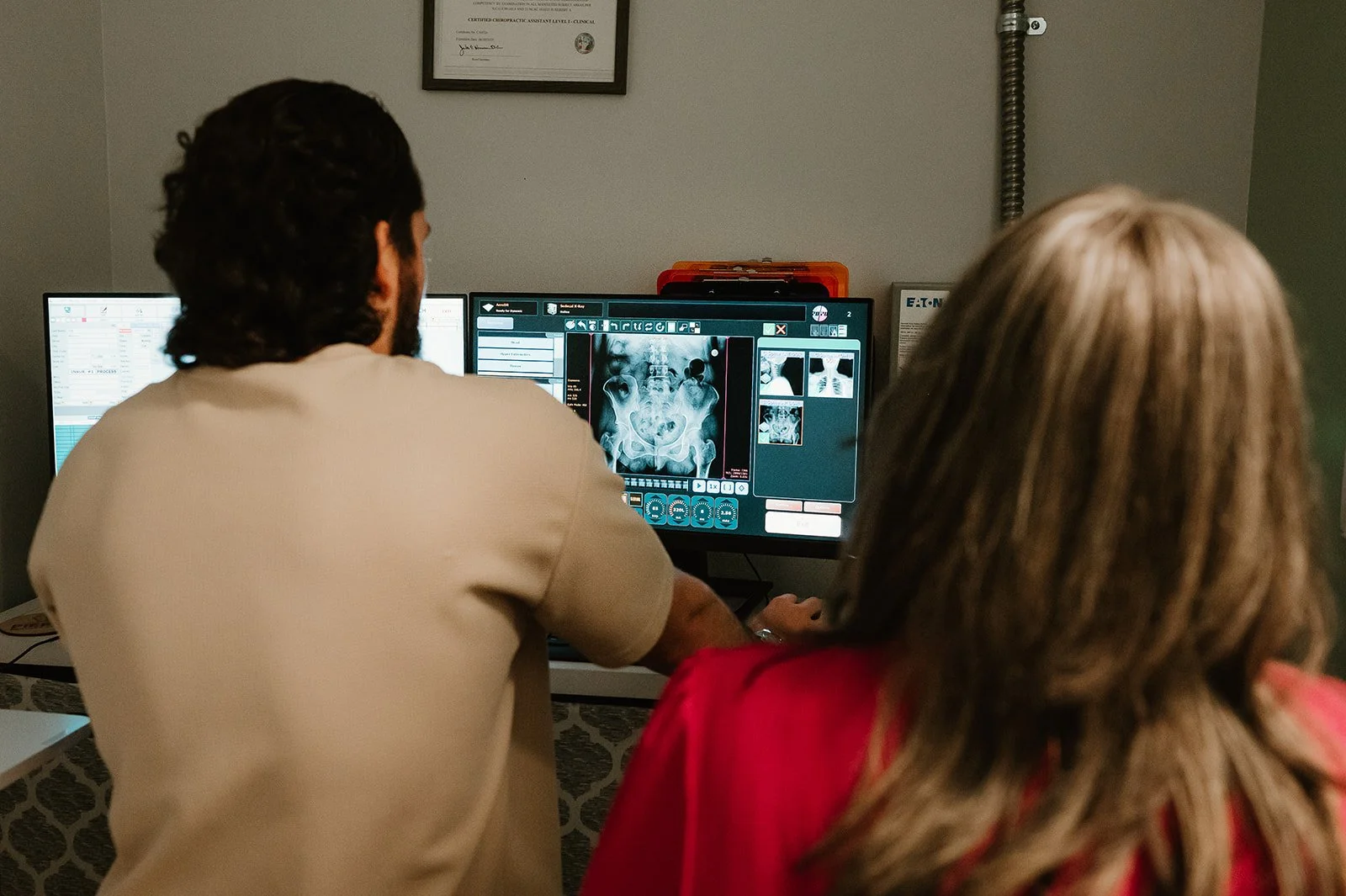 Chiropractor reviewing spinal X-rays with a patient to understand the cause of symptoms