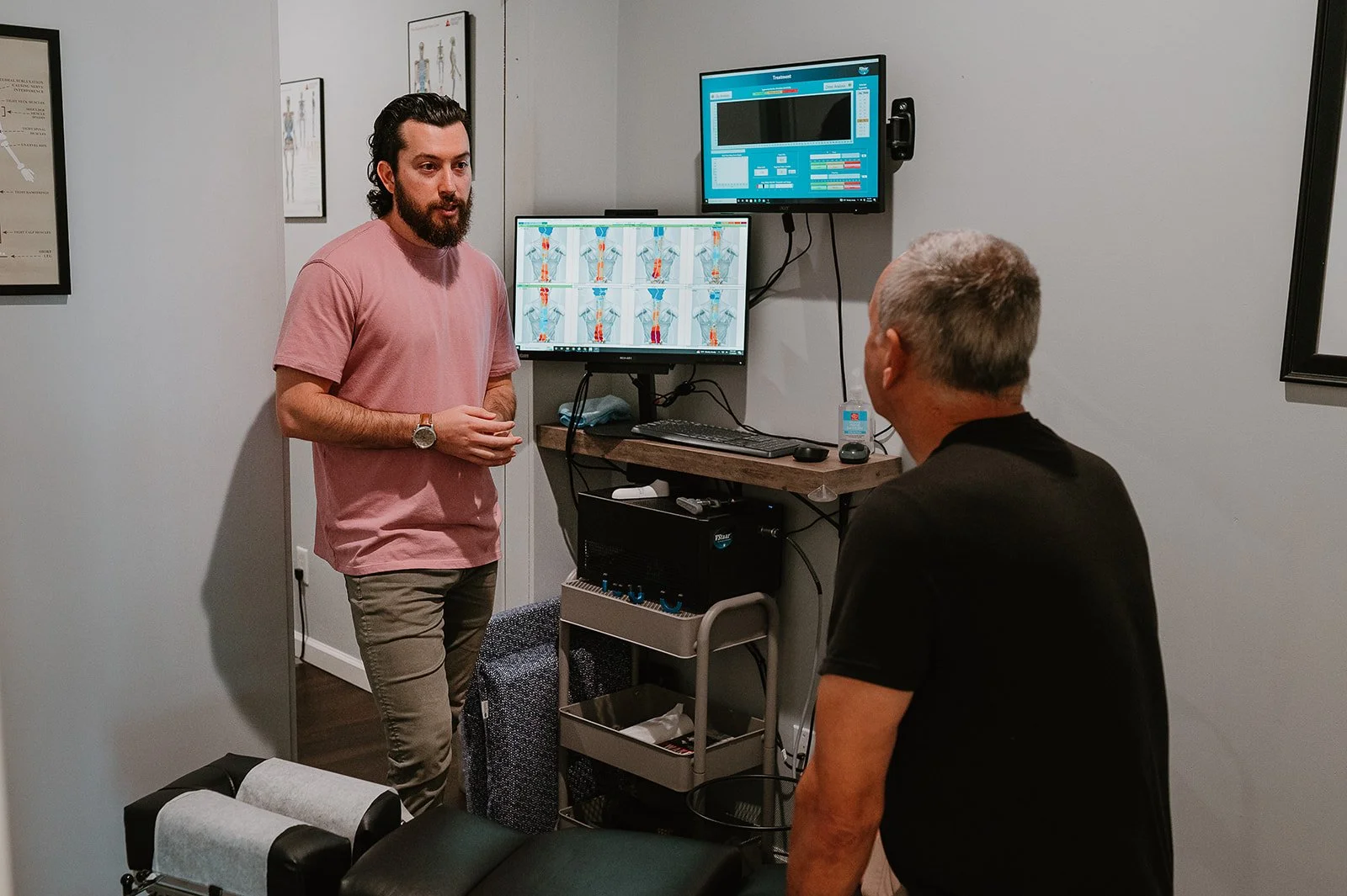 Chiropractor explaining digital nerve scan results to a patient during a chiropractic consultation