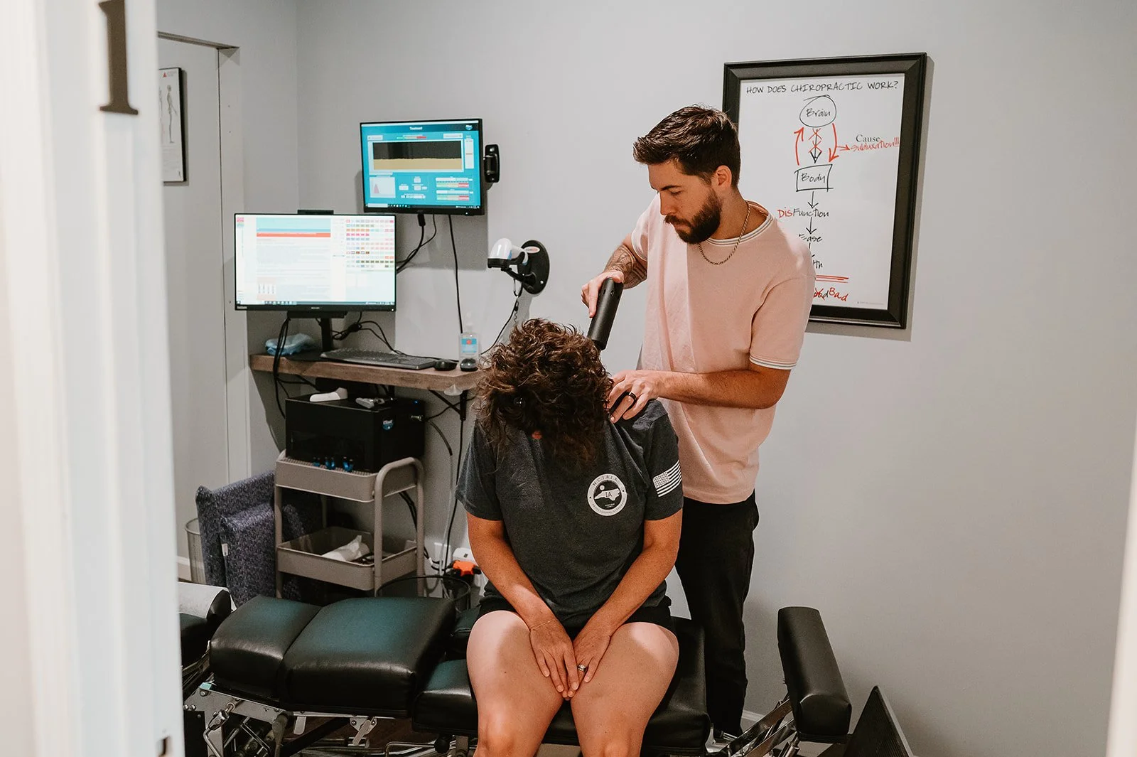 Chiropractor performing a gentle instrument-assisted adjustment for an adult patient at MCH Chiropractic and Nutrition in Matthews, NC