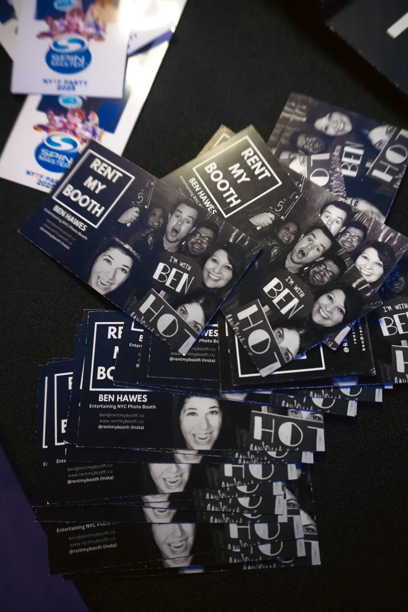Flyers and cards advertising a photo booth rental service called 'Rent My Booth' by Ben Hawes. The cards feature group photos and text details such as website and Instagram handle.