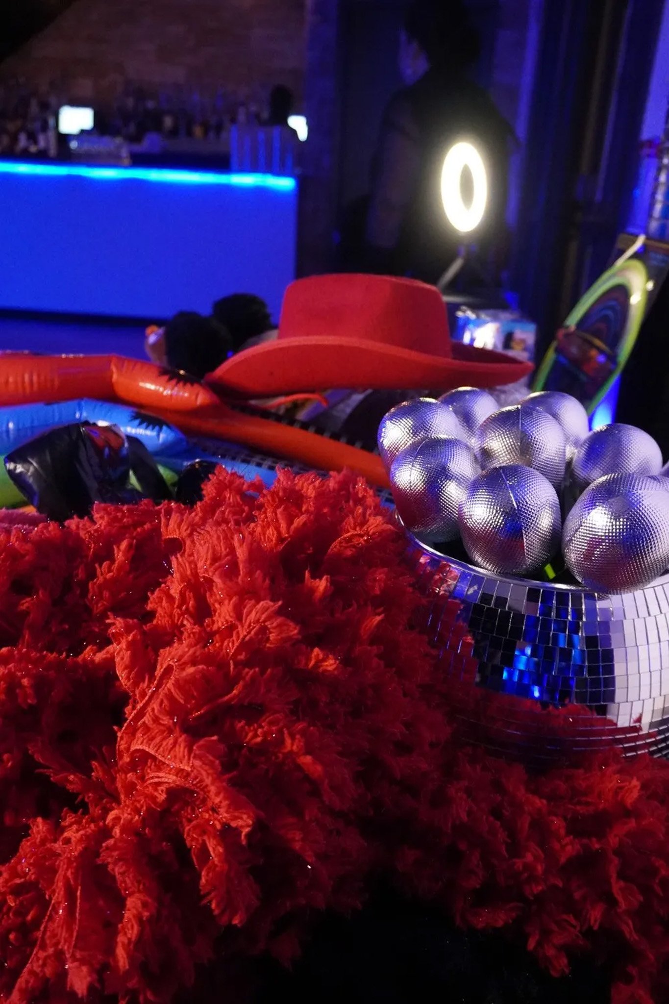 Red cowboy hat, disco ball, silver balls, and red cloth in a blue-lit room.