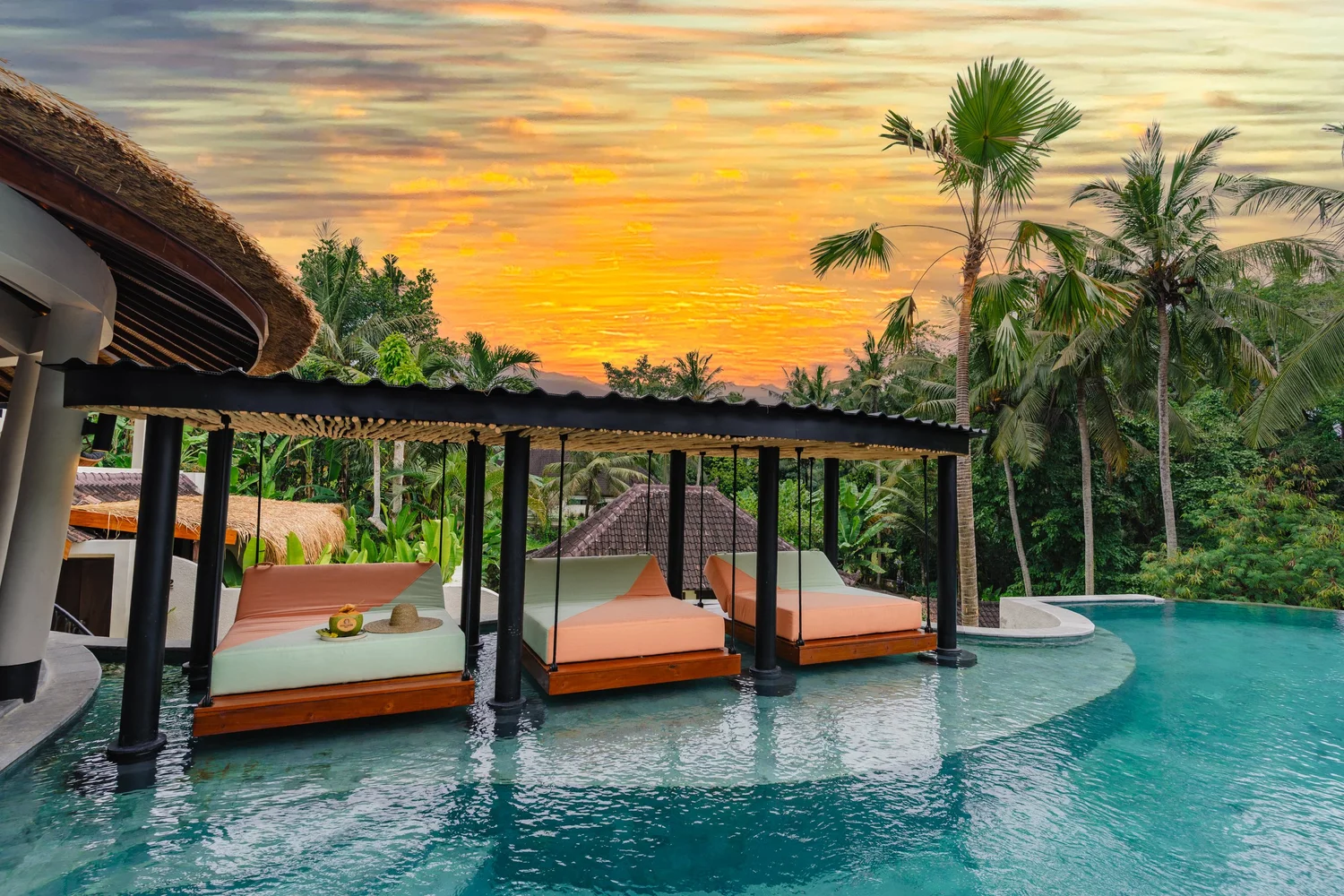 Infinity pool with sunset over Bali landscape