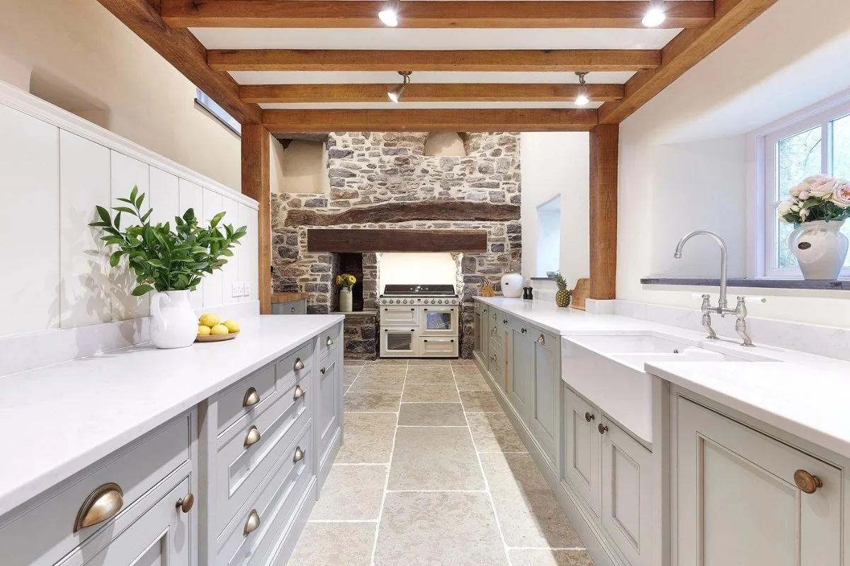 A very bright kitchen with off white cabinets and natural wood beams.