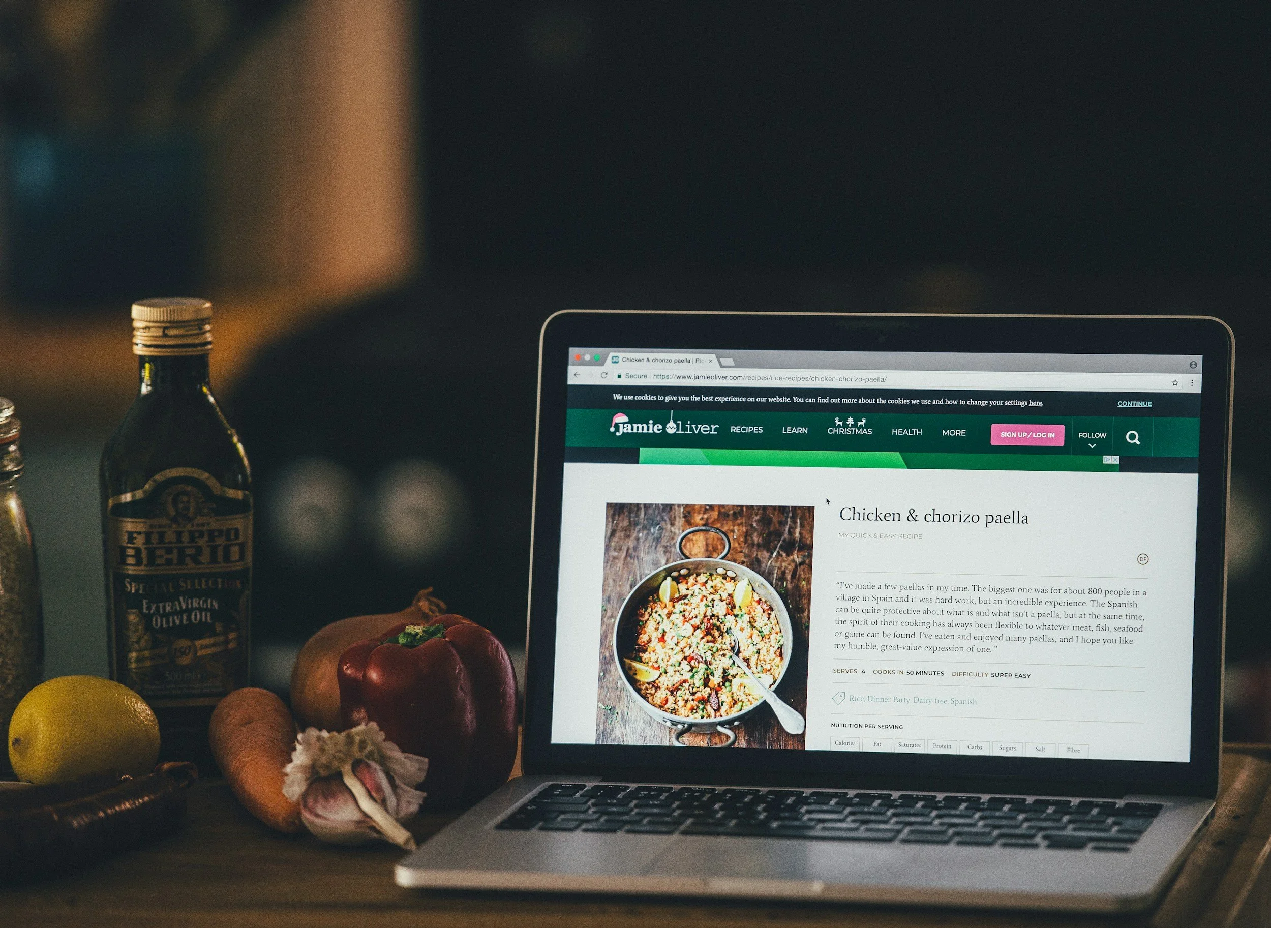 laptop sitting on a counter top with a recipe for Chicken and Chorizo paella on the screen