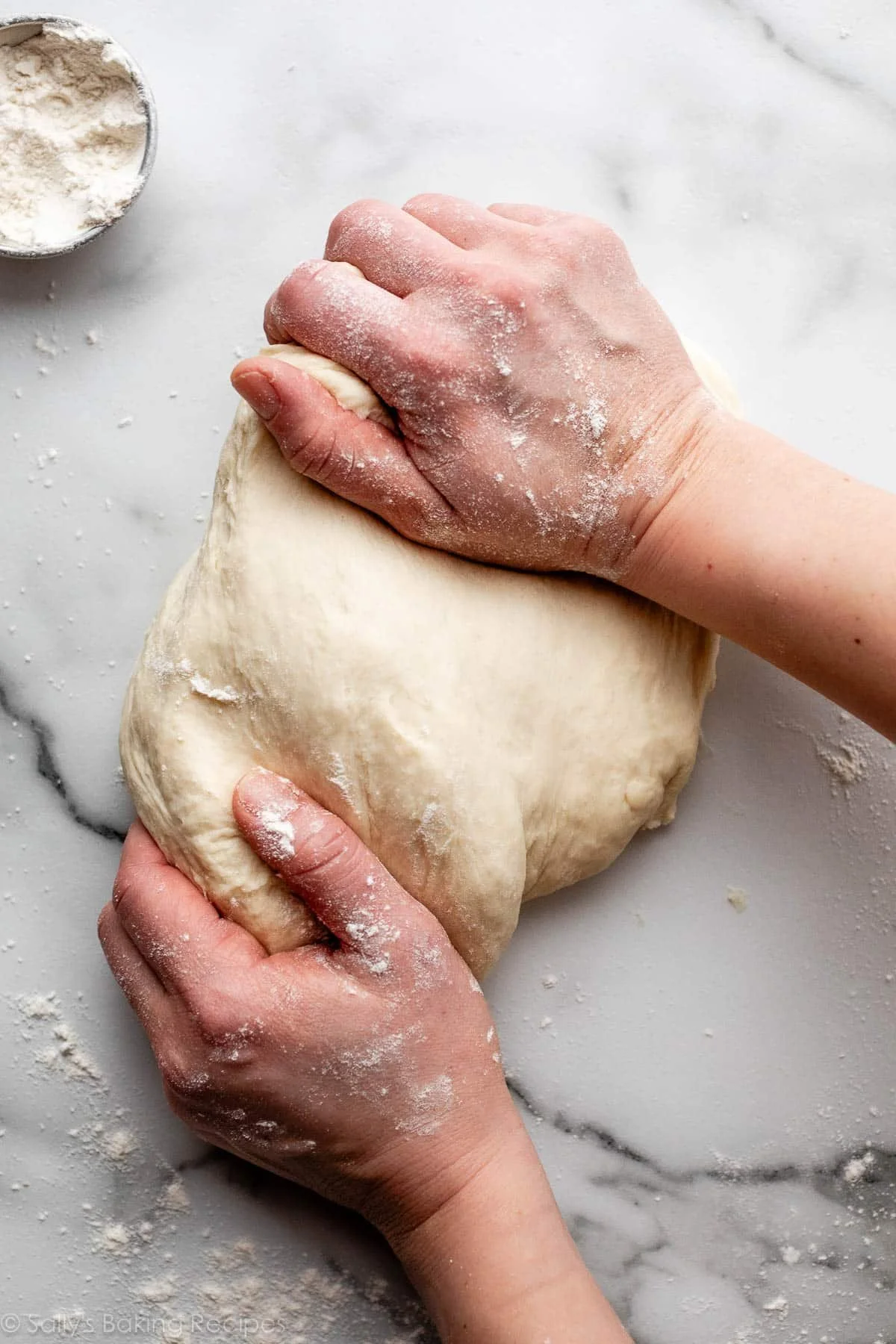 flour coated hands kneading bread dough