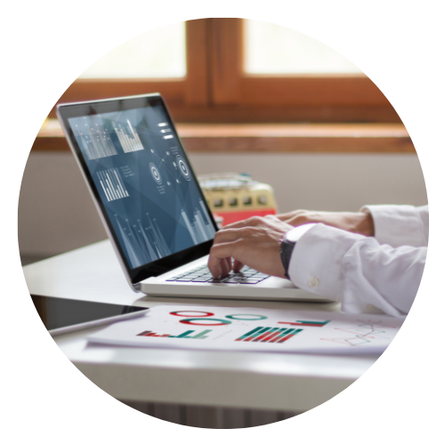 Person working on a laptop at a desk with financial charts and data displayed on the screen.