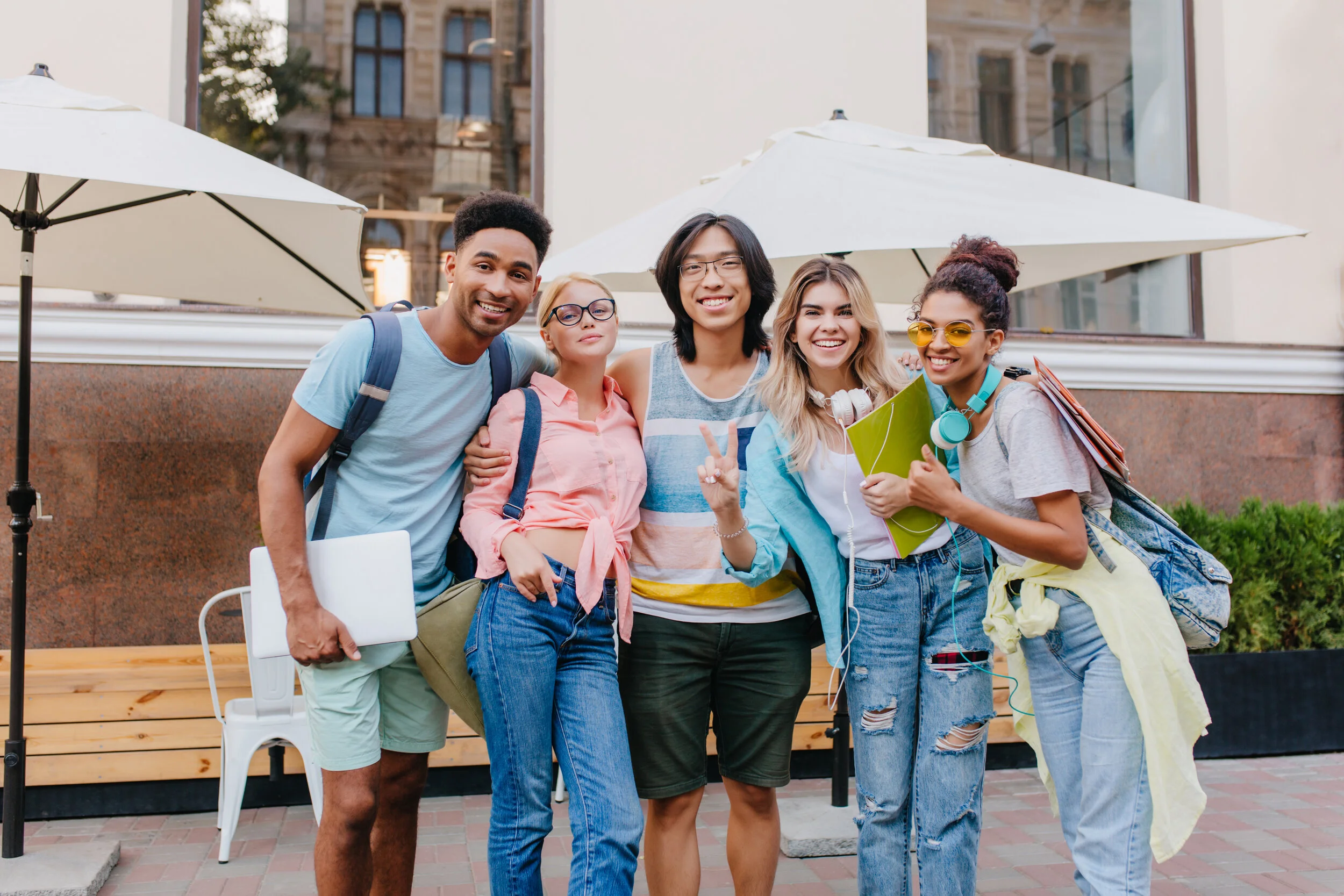 laughing-asian-boy-glasses-shorts-embracing-charming-blonde-girls-front-outdoor-cafe-joyful-students-came-open-air-restaurant-celebrate-end-exams.jpg