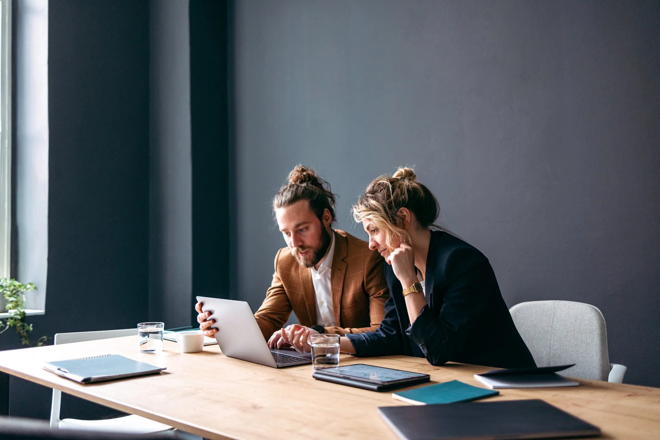 En dame og en mann som sitter foran en PC med et vannglass