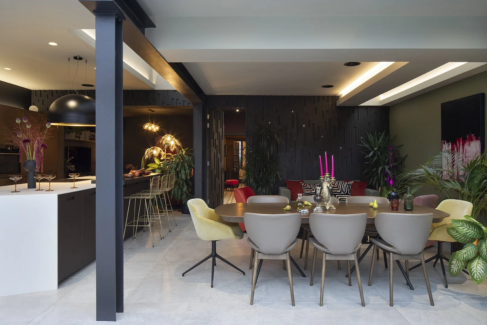 Open-plan dining area with large dark oak extendable dining table, mixed dining chairs in taupe leather and velvet ochre, slatted dark wall panel, wave extractor pendant light and pink candles, Queens Road Whitley Bay