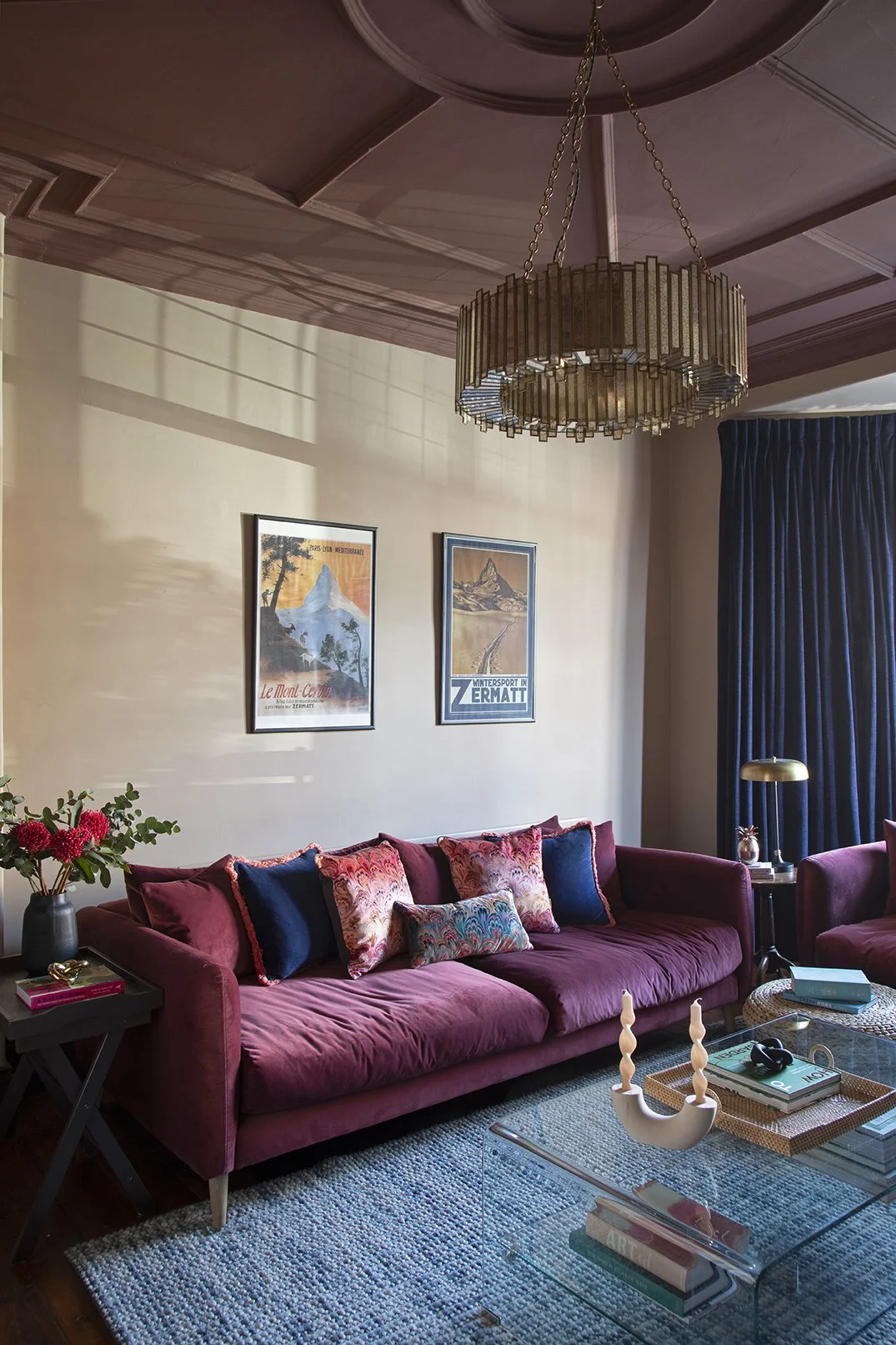 Sitting room in the Queens Road project by Carole Crowe Interior Design, Whitley Bay, featuring a large plum velvet sofa styled with navy velvet and multicoloured marbled print cushions with coral fringing, a brass and glass drum chandelier hanging f