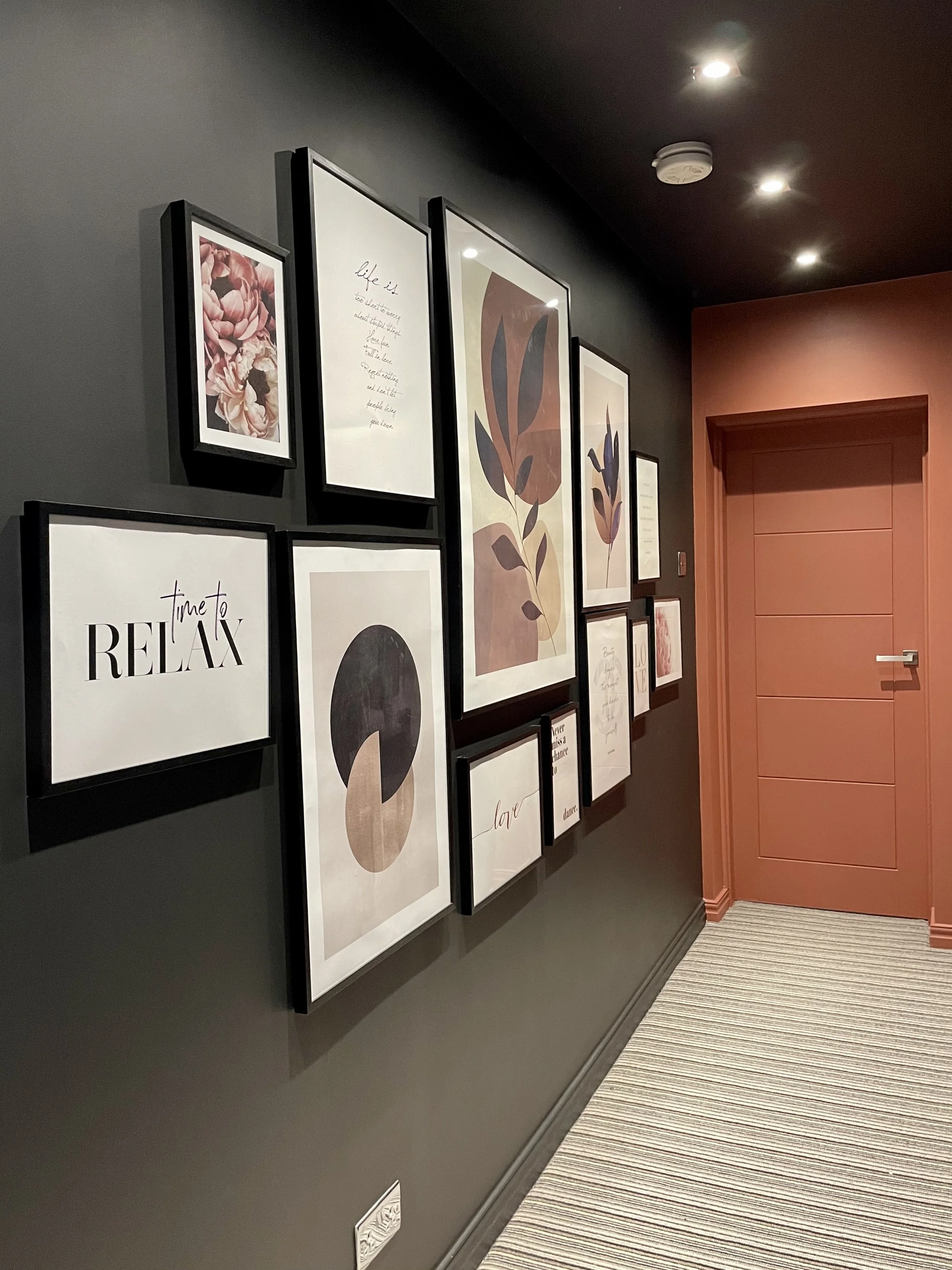 Gallery wall with framed botanical and typographic prints in a dark hallway, Tynemouth interior design project