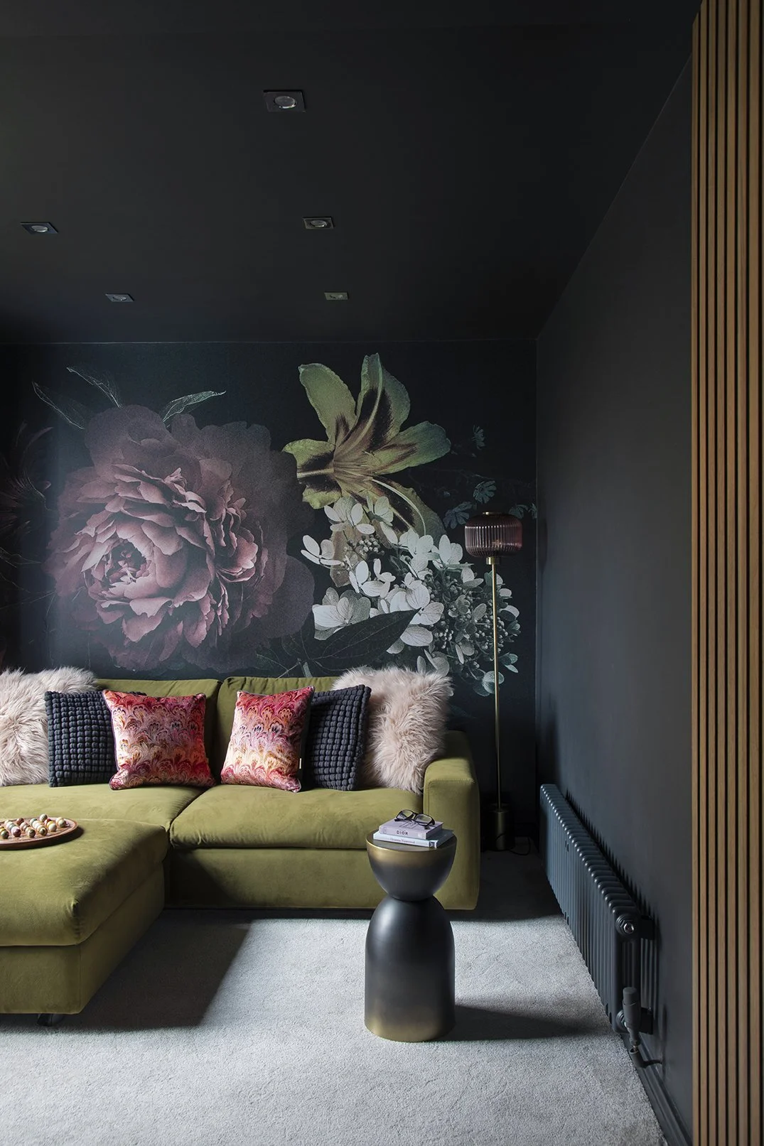 Full view of hidden snug with dark floral mural, olive green corner sofa, black side table and oak wood slat panelling, Lytham Road Tynemouth