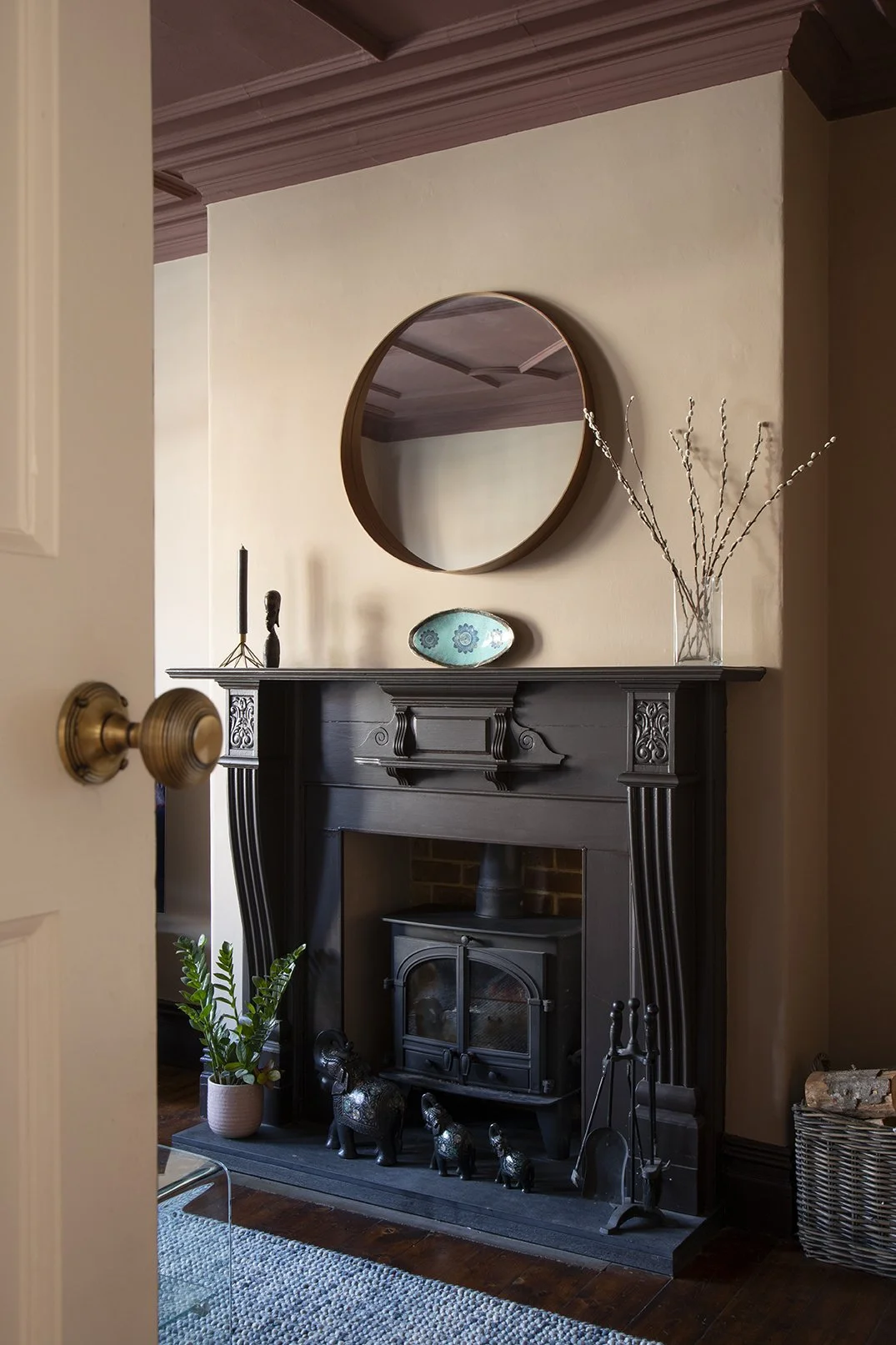 Victorian fireplace in the sitting room of the Queens Road project by Carole Crowe Interior Design, Whitley Bay, painted in deep charcoal with ornate carved detailing, housing a cast iron wood-burning stove with a decorative collection of small black