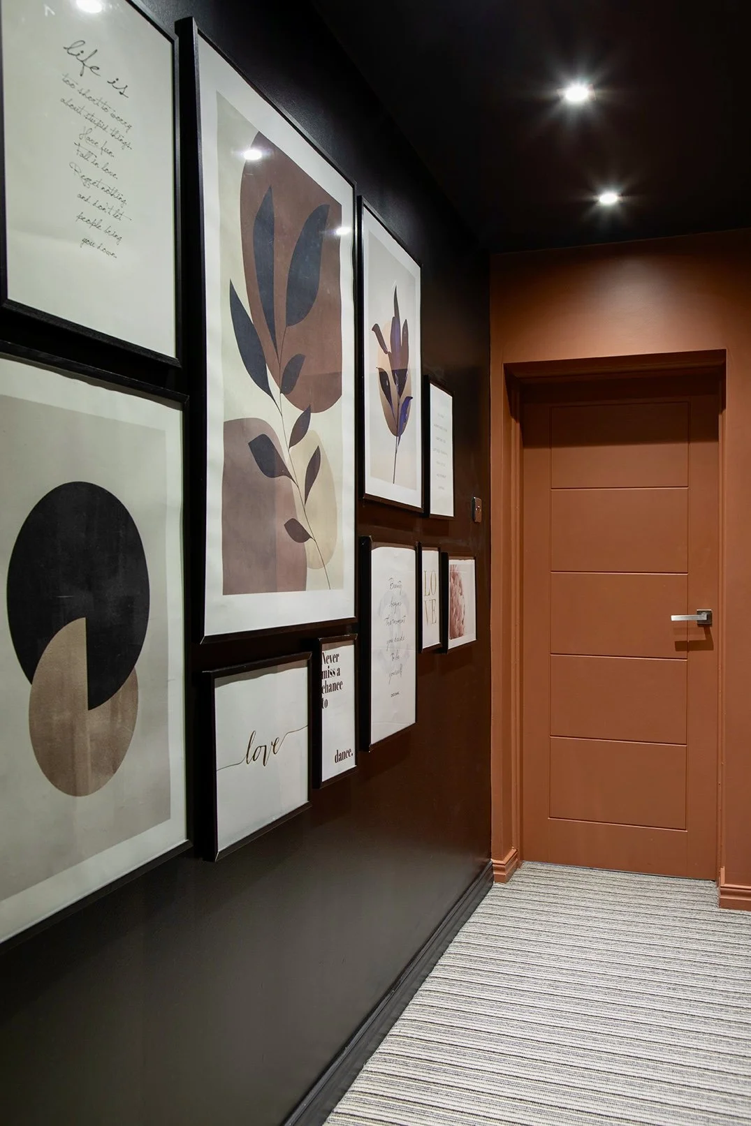 Dark landing hallway with gallery wall of framed botanical and typographic prints, terracotta painted door, Lytham Road Tynemouth