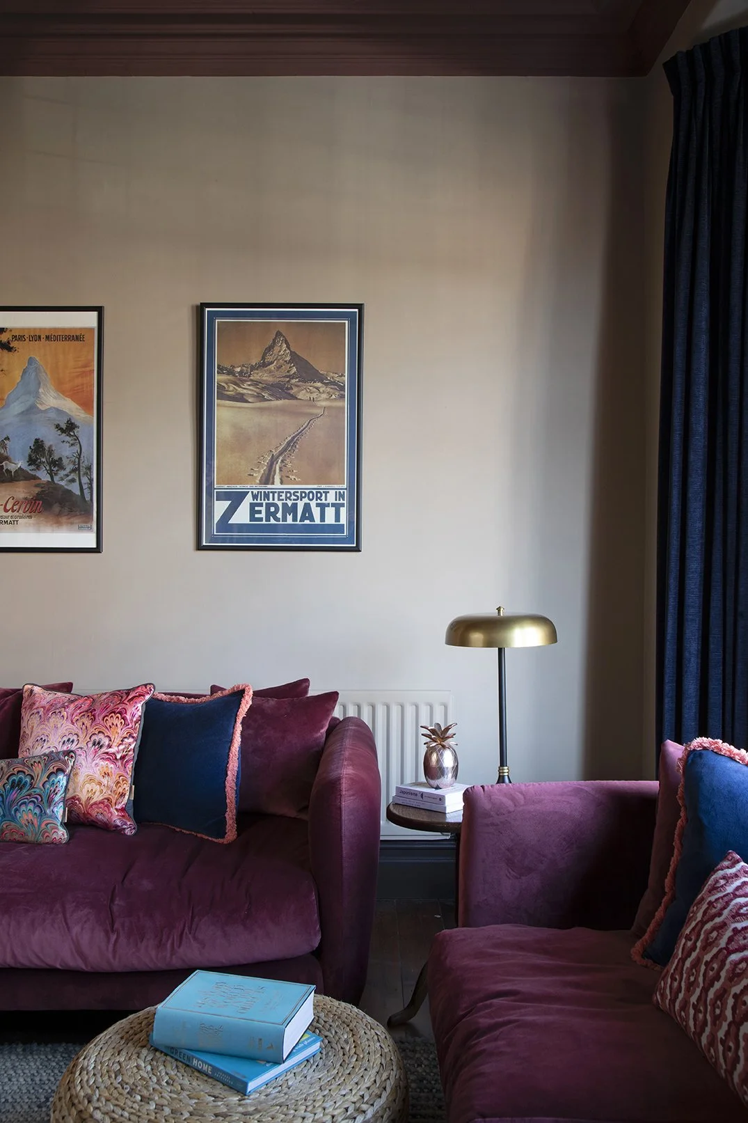 Sitting room seating detail in the Queens Road project by Carole Crowe Interior Design, Whitley Bay, featuring two plum velvet sofas with multicoloured marbled print and navy velvet cushions with coral fringing, vintage Alpine ski travel posters hung