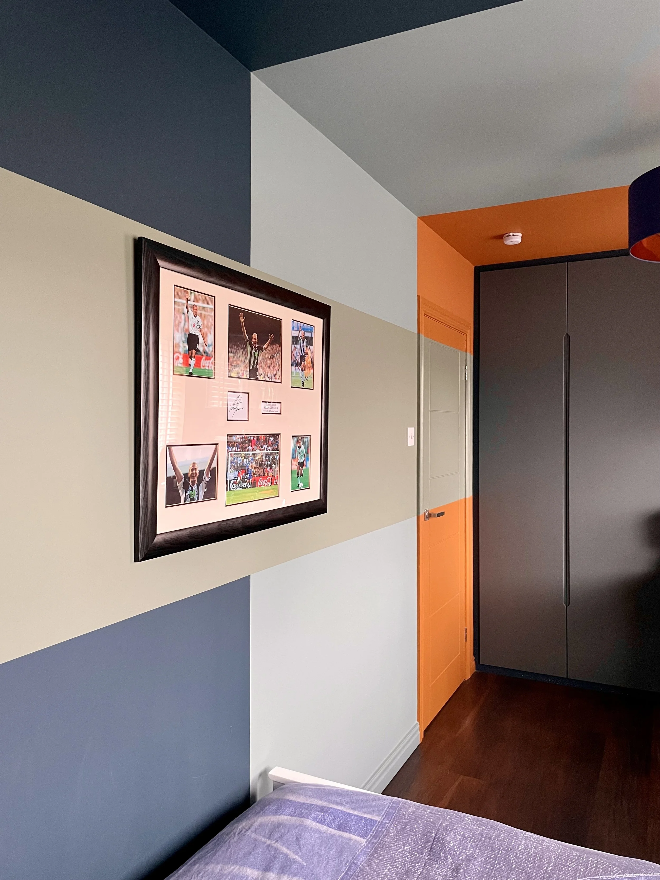 Boys' bedroom with framed signed football memorabilia on multi-tone colour-blocked feature wall, Tynemouth