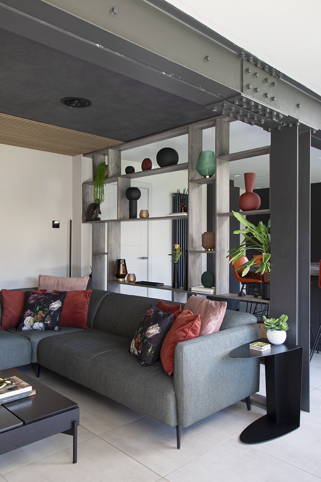 Open-plan living area with green corner sofa, floral cushions, bespoke display shelving and painted exposed steel RSJ beam, Lytham Road Whitley Bay