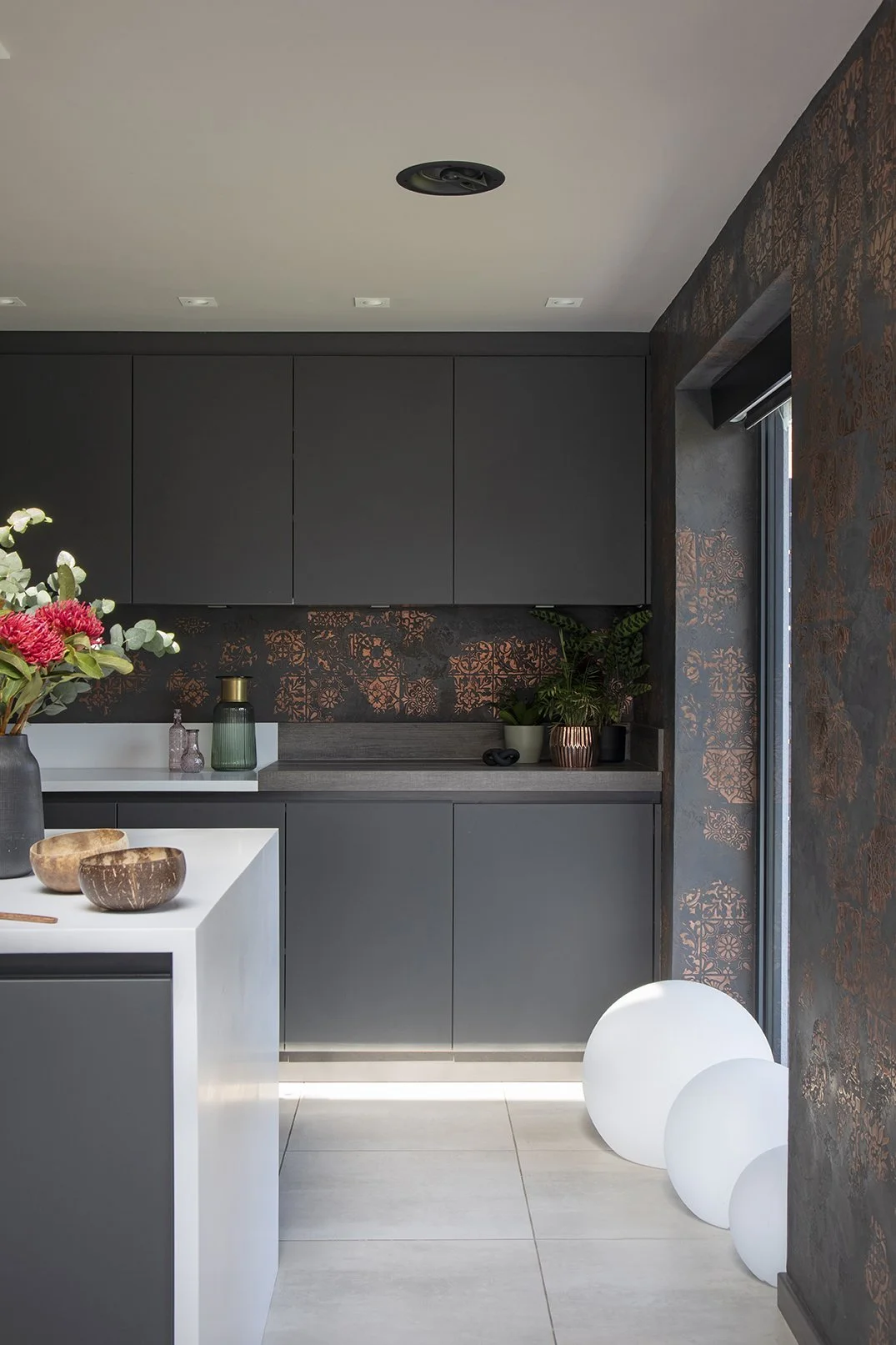 Dark matt grey handleless kitchen with black and copper Venetian plaster splashback, white globe floor lights and white island worktop, Lytham Road Whitley Bay