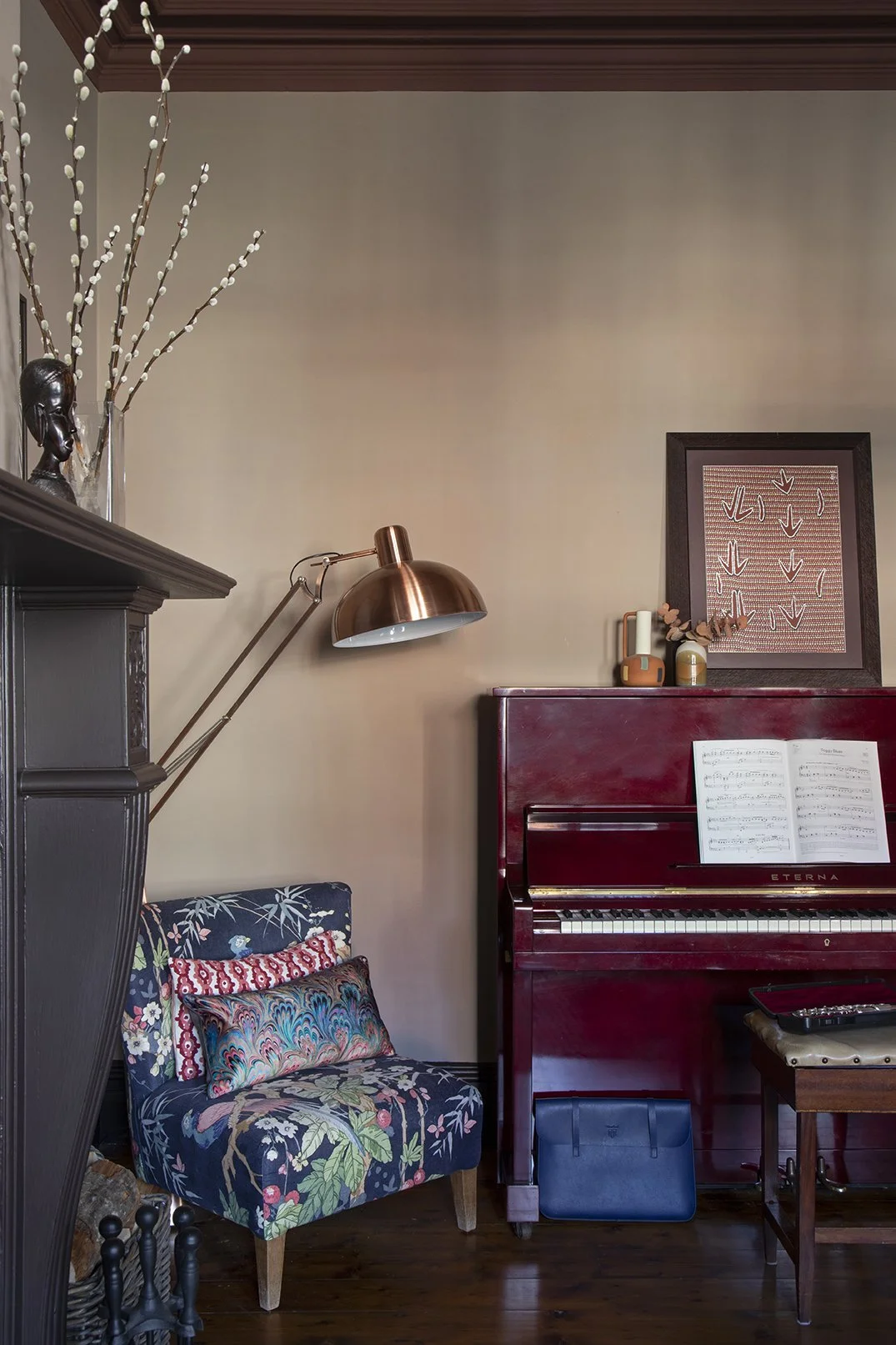 Corner detail of the sitting room in the Queens Road project by Carole Crowe Interior Design, Whitley Bay, featuring a glossy deep red Eterna upright piano with sheet music open, a small armchair upholstered in a bold dark navy botanical print fabric