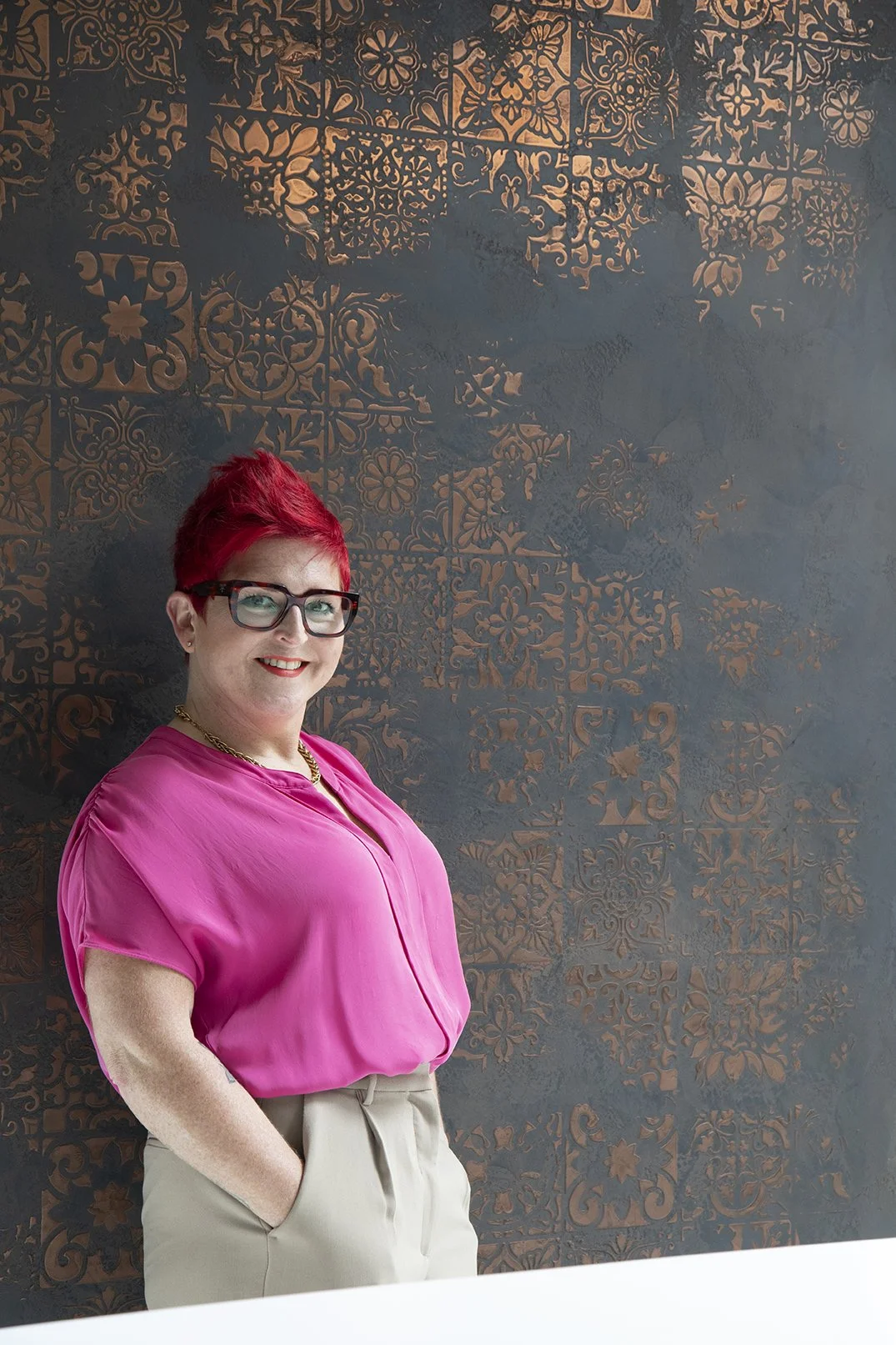 Interior designer Carole Crowe standing in front of black and copper Venetian plaster feature wall, Lytham Road Tynemouth project