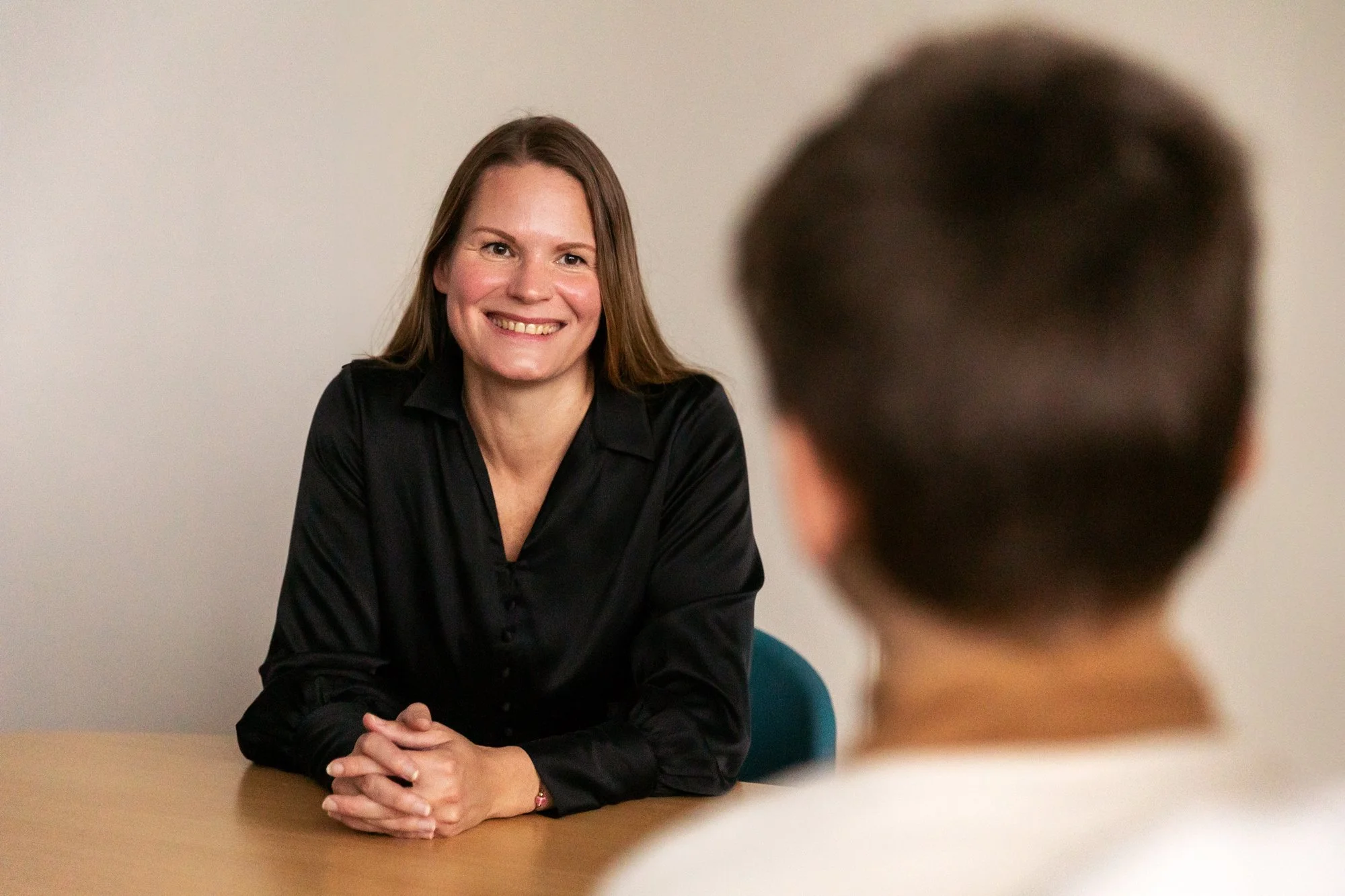 Smilende terapeut i sort skjorte i samtale med klient