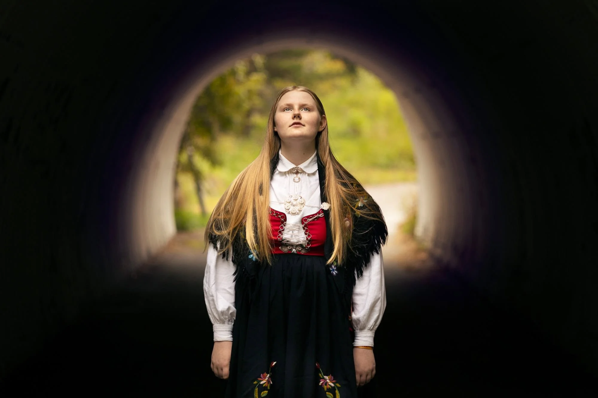 Konfirmant i bunad fotografert i tunnel med arkitektur som ramme
