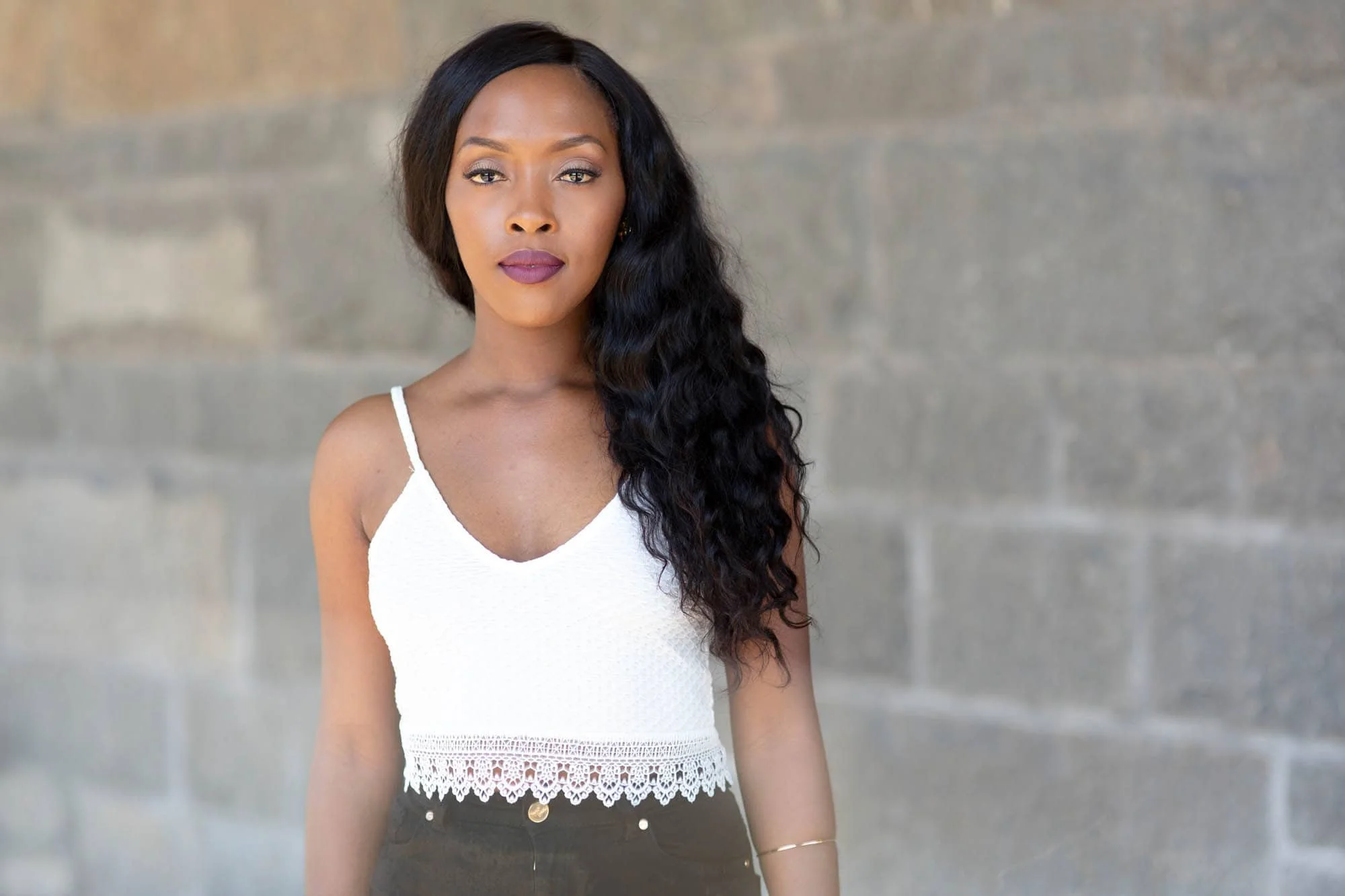 Ung kvinne med hvit topp mot murvegg