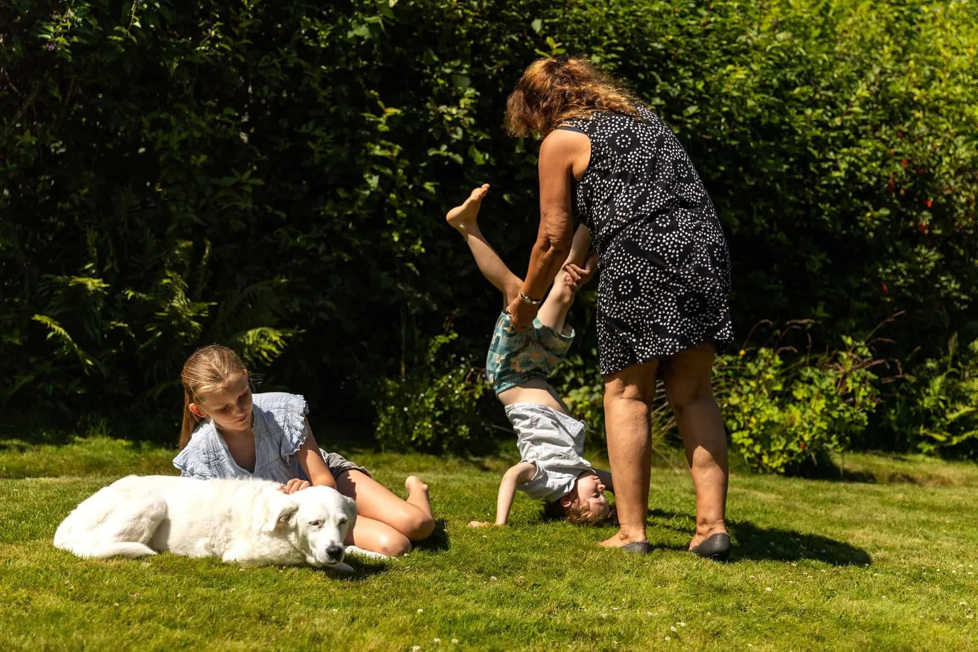 Luna ligger på gresset ved siden av et barn som leker i hagen