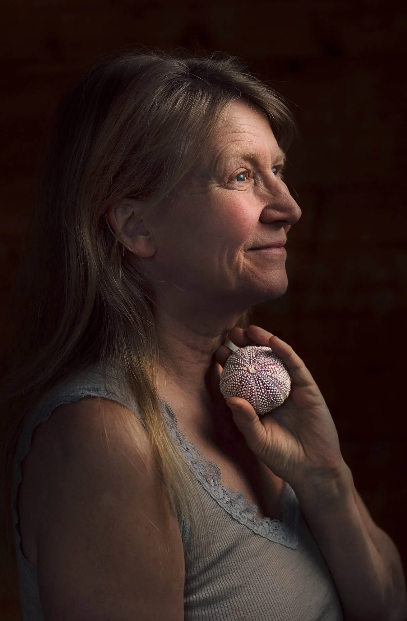 Kunstnerisk portrett av eldre kvinne i profil som holder en kråkebolle